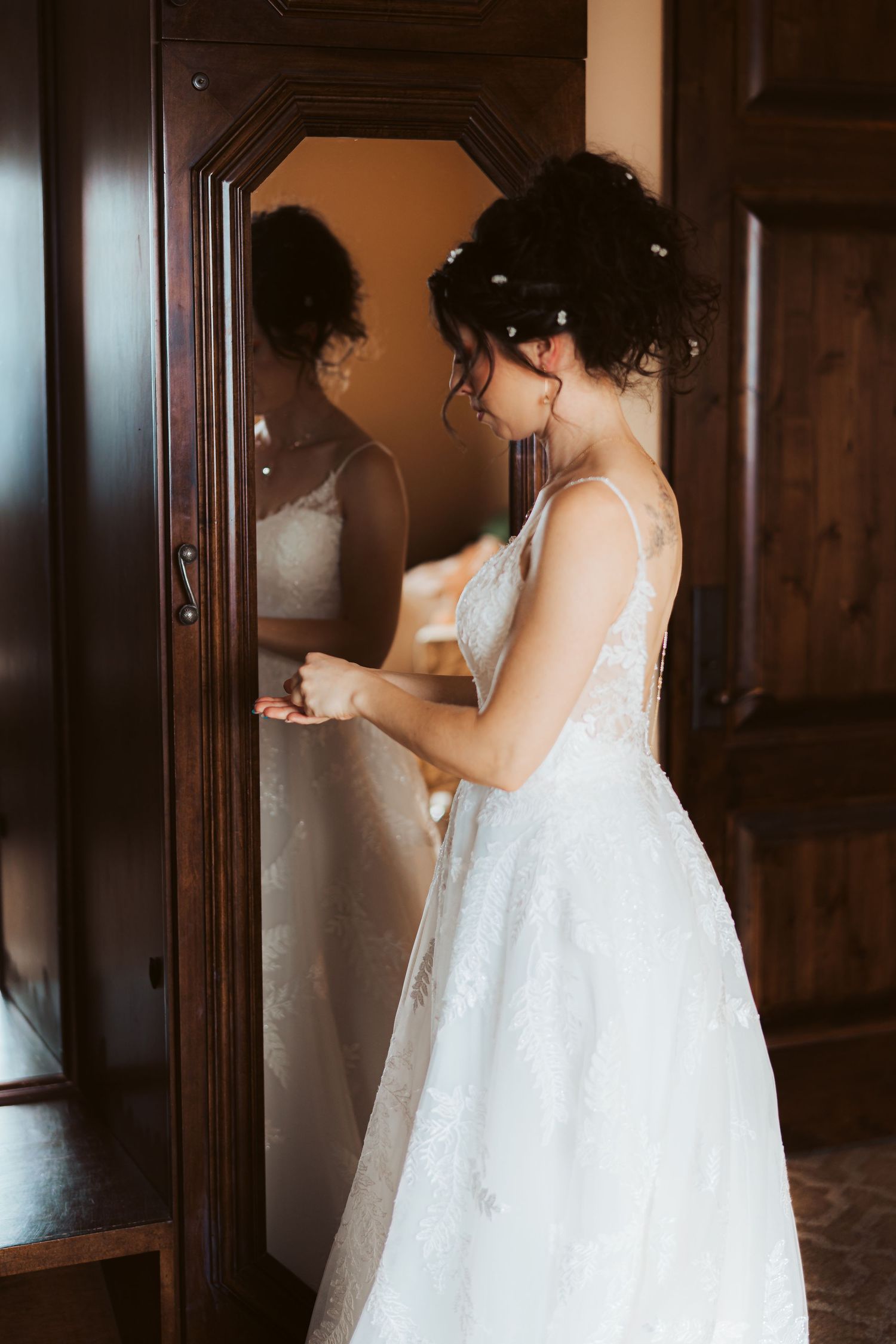 A side view of a white wedding dress being reflected in a wooden framed mirror.