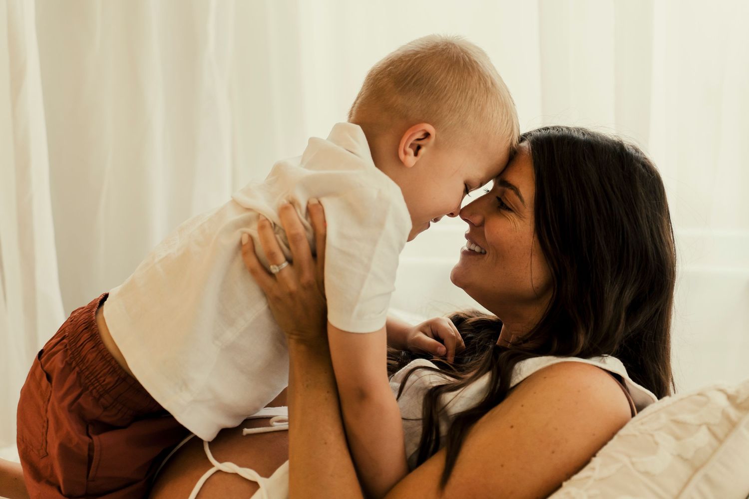 A tender moment between parent and baby in a bright, sunlit room.