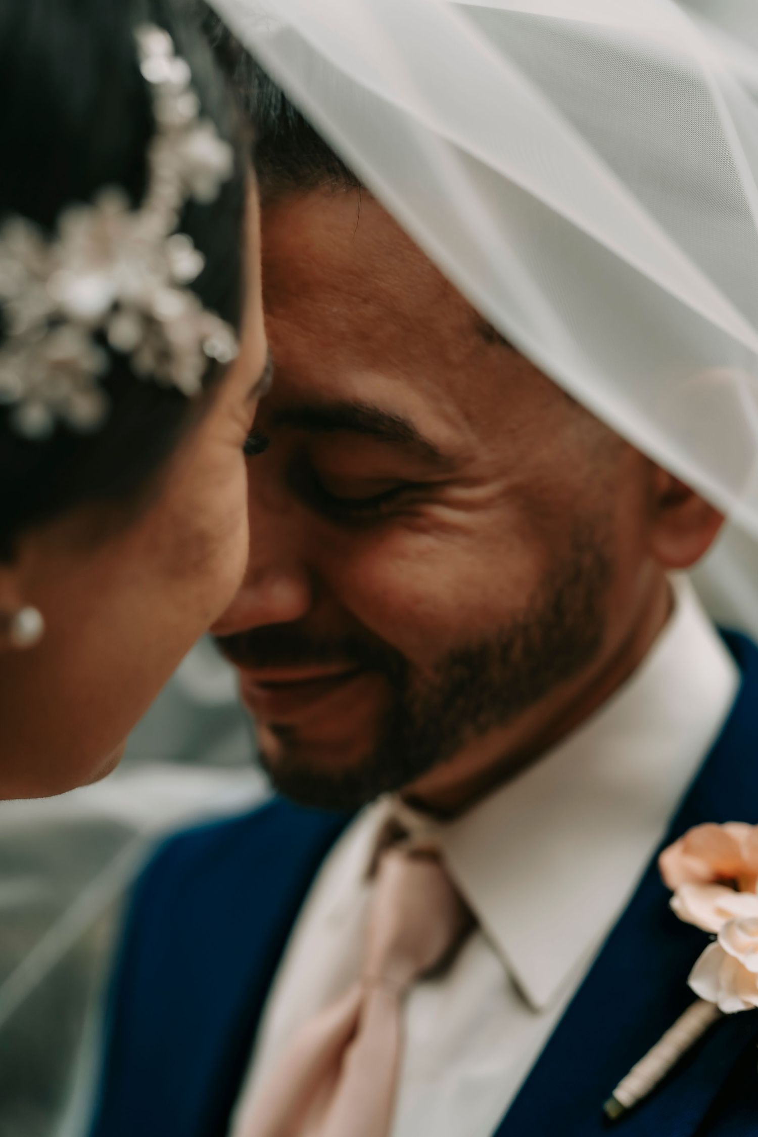 Intimate close-up moment of a couple sharing a tender moment under a bridal veil.