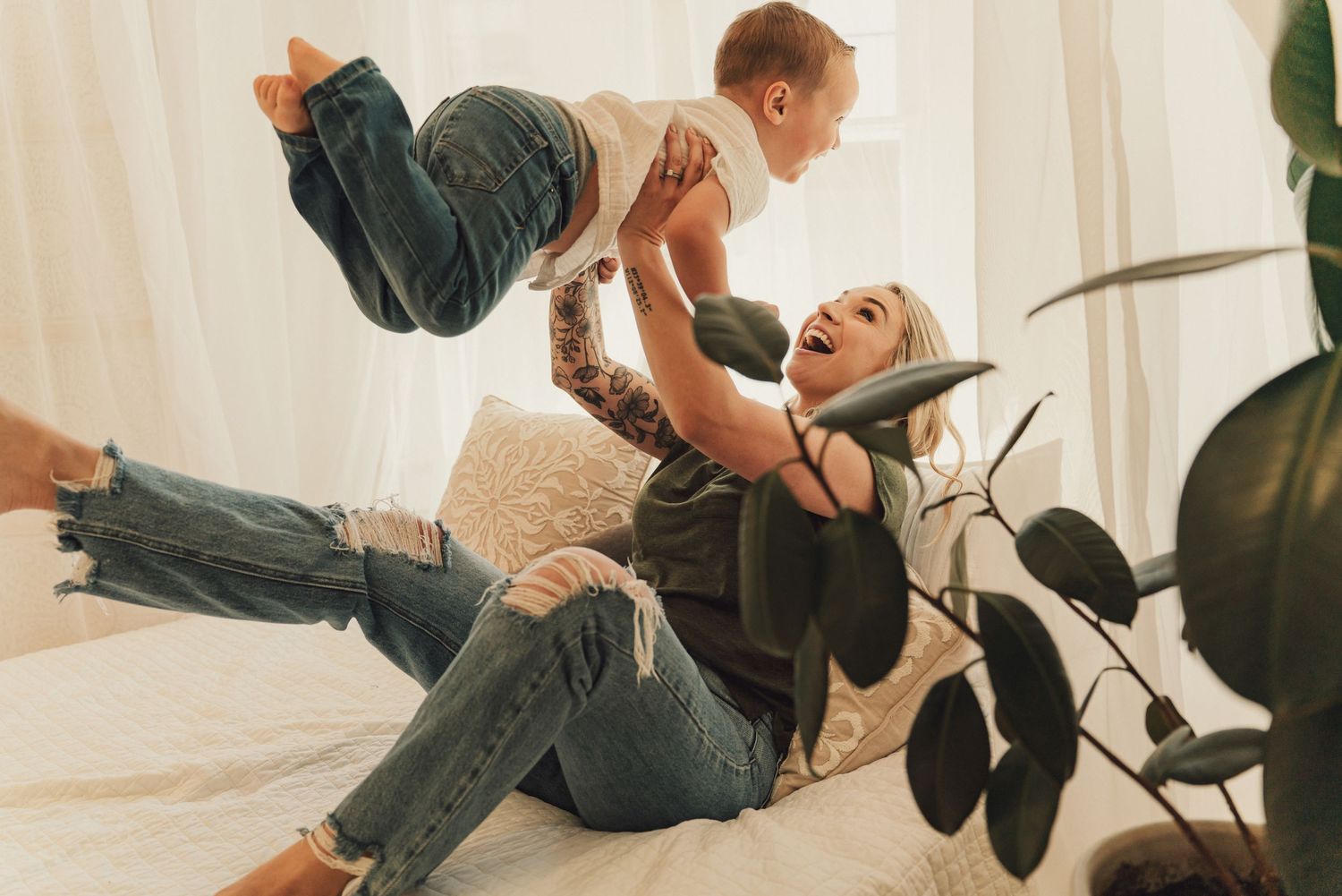 Parent and child playing together on couch with joyful expressions.