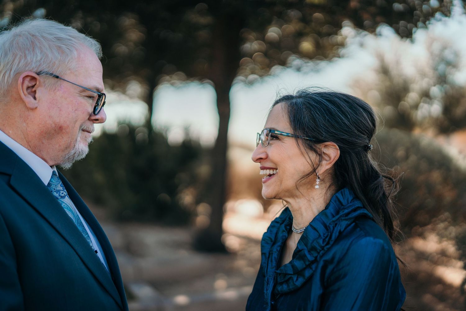 Elegant mature couple in formal attire sharing intimate moment outdoors.