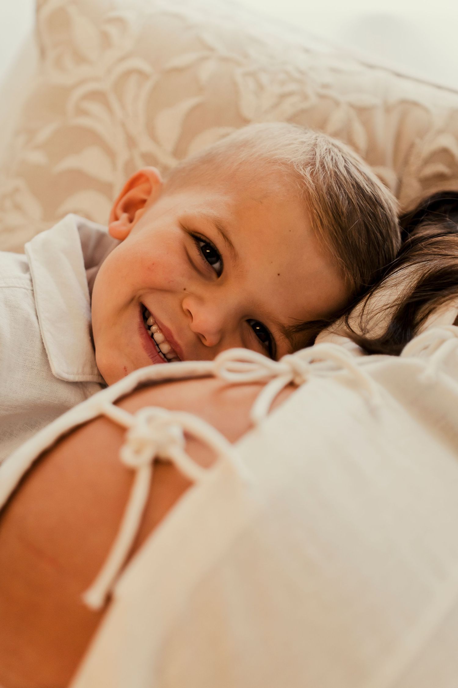 Soft morning light illuminates a child resting on white linens.