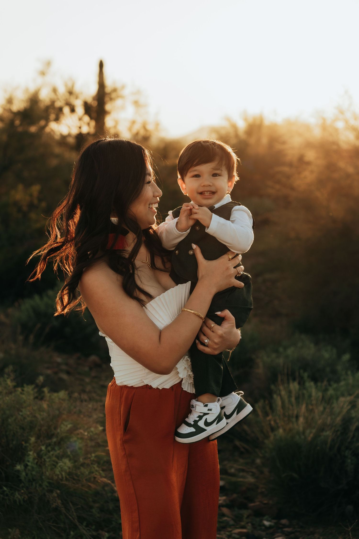 A parent and child share playful moments together at sunset in a desert landscape.