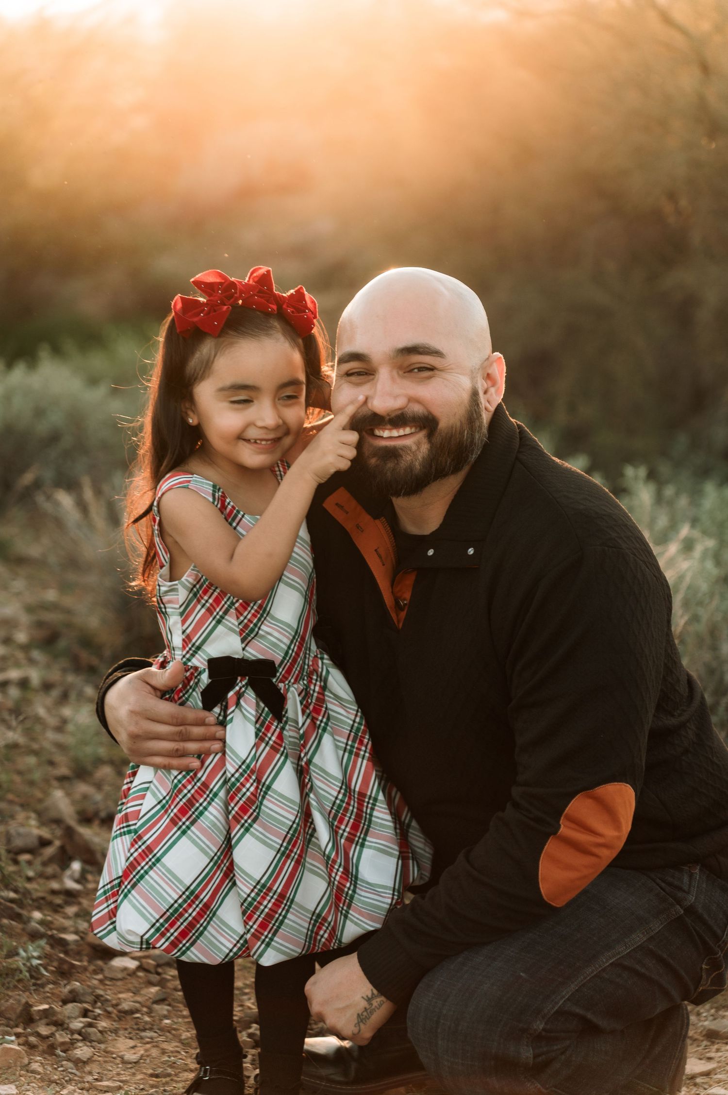 A heartwarming outdoor portrait at sunset shows a special moment between two people in a natural setting.
