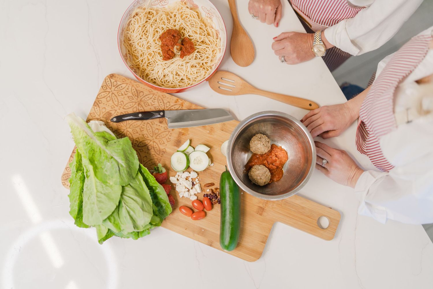 Overhead view of bagels and sandwich ingredients spread across a wooden cutting board and white surface.