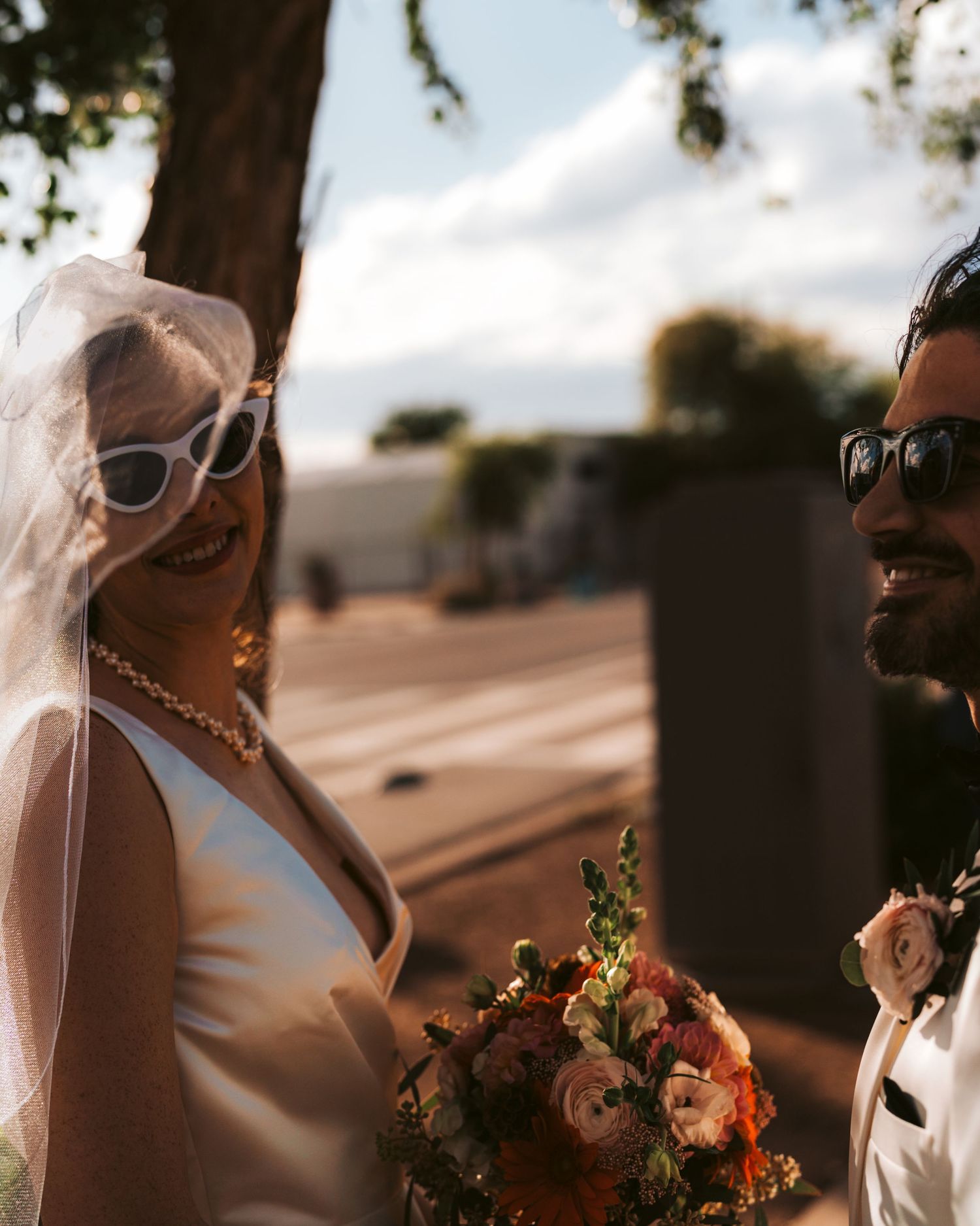 Sunlit wedding portrait with colorful bouquet during outdoor ceremony.