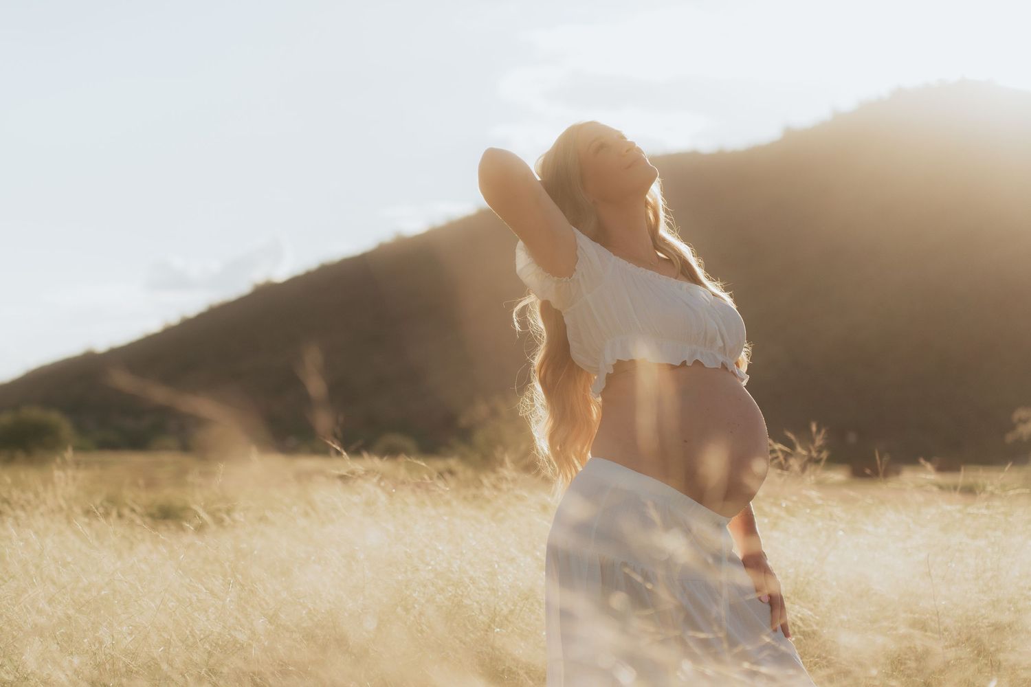Silhouetted figures walk through a sunlit golden meadow during sunset creating a dreamy atmosphere.