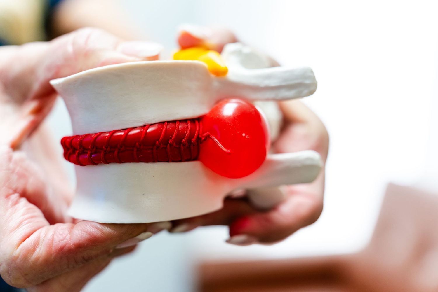 Close-up view of a red and white plastic measuring spoon with liquid medicine being poured into it.