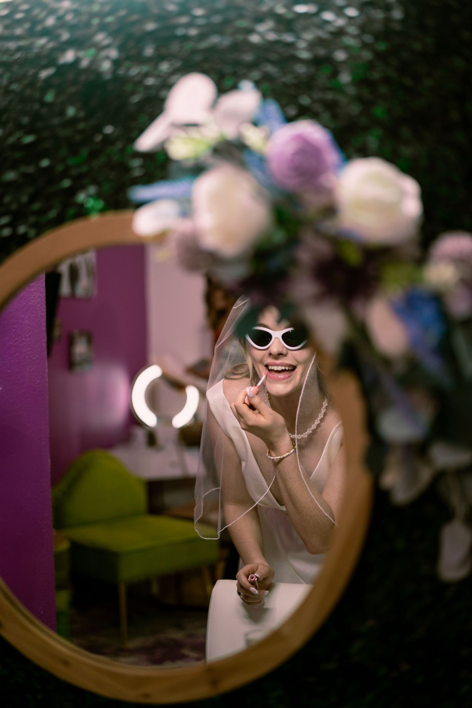 Joyful reflection in round mirror with floral decorations above.