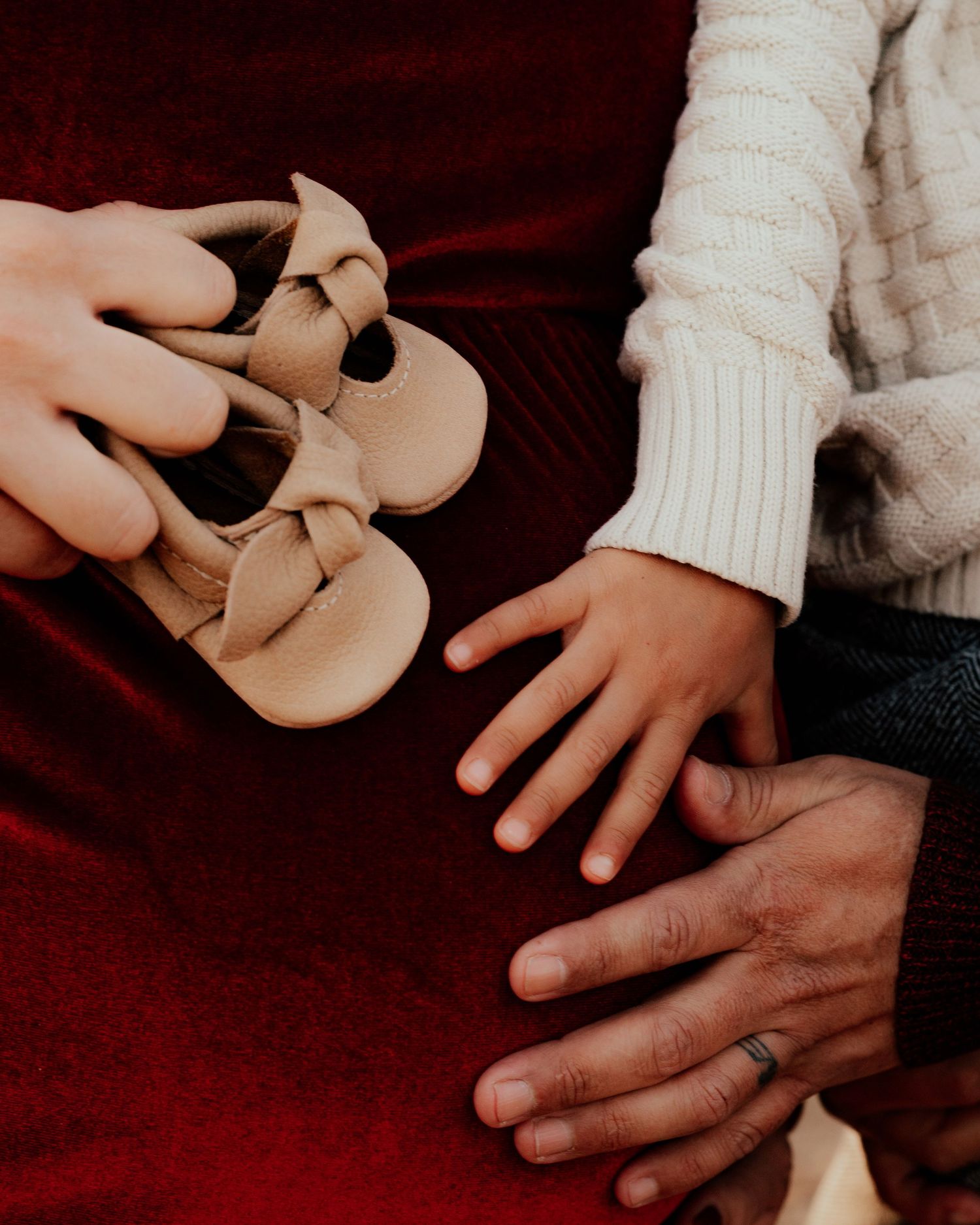 Close-up of hands tenderly touching during a pregnancy photo session.
