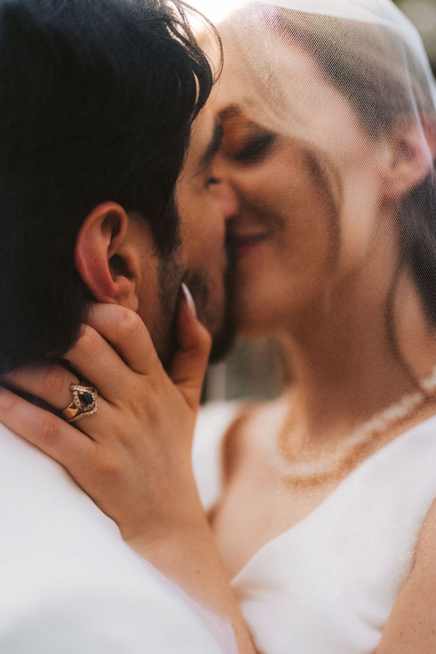 A tender close-up moment showing an engagement ring during an intimate kiss.
