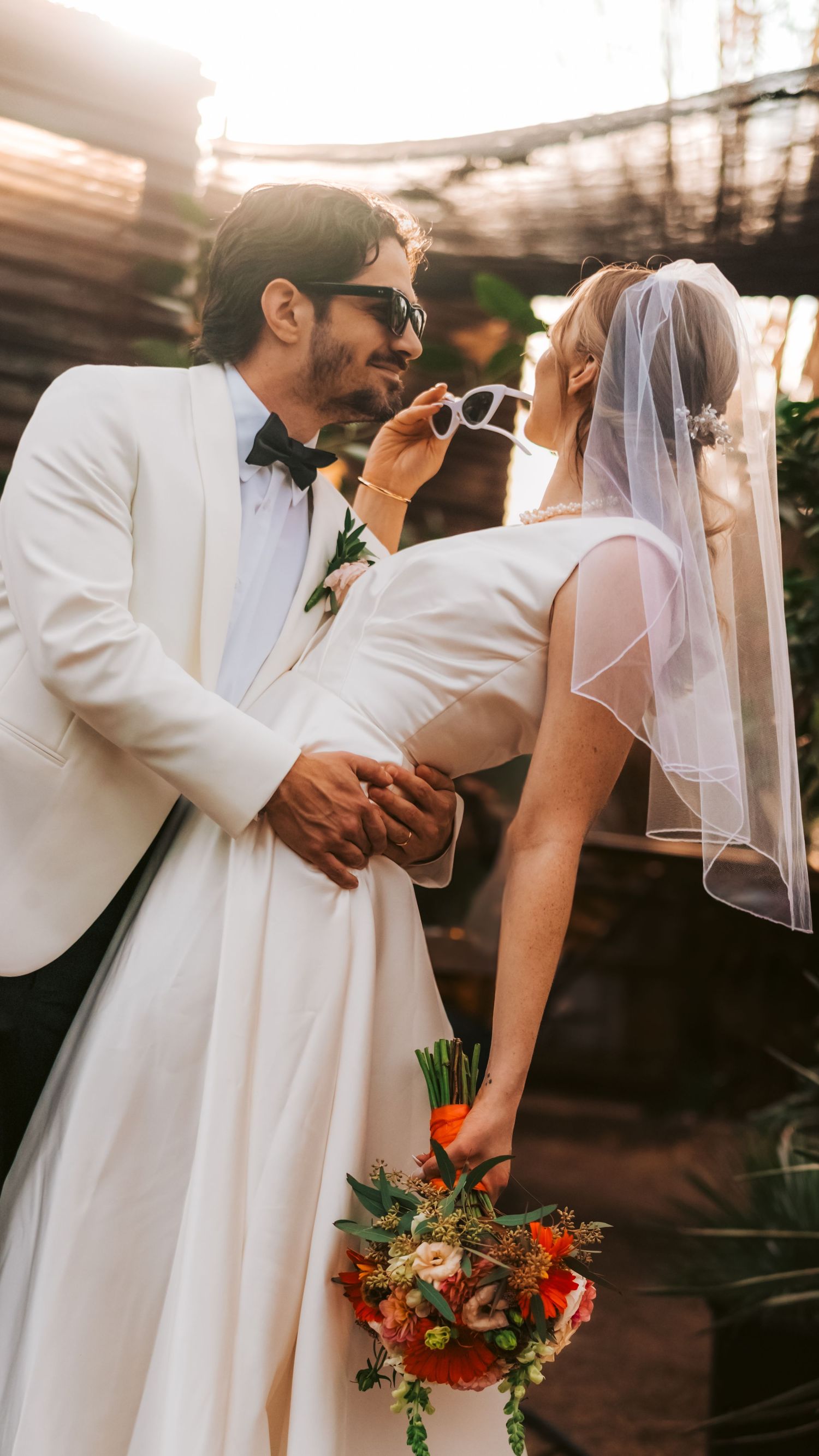 A romantic wedding moment captured in warm sunlight with the couple in elegant white attire.