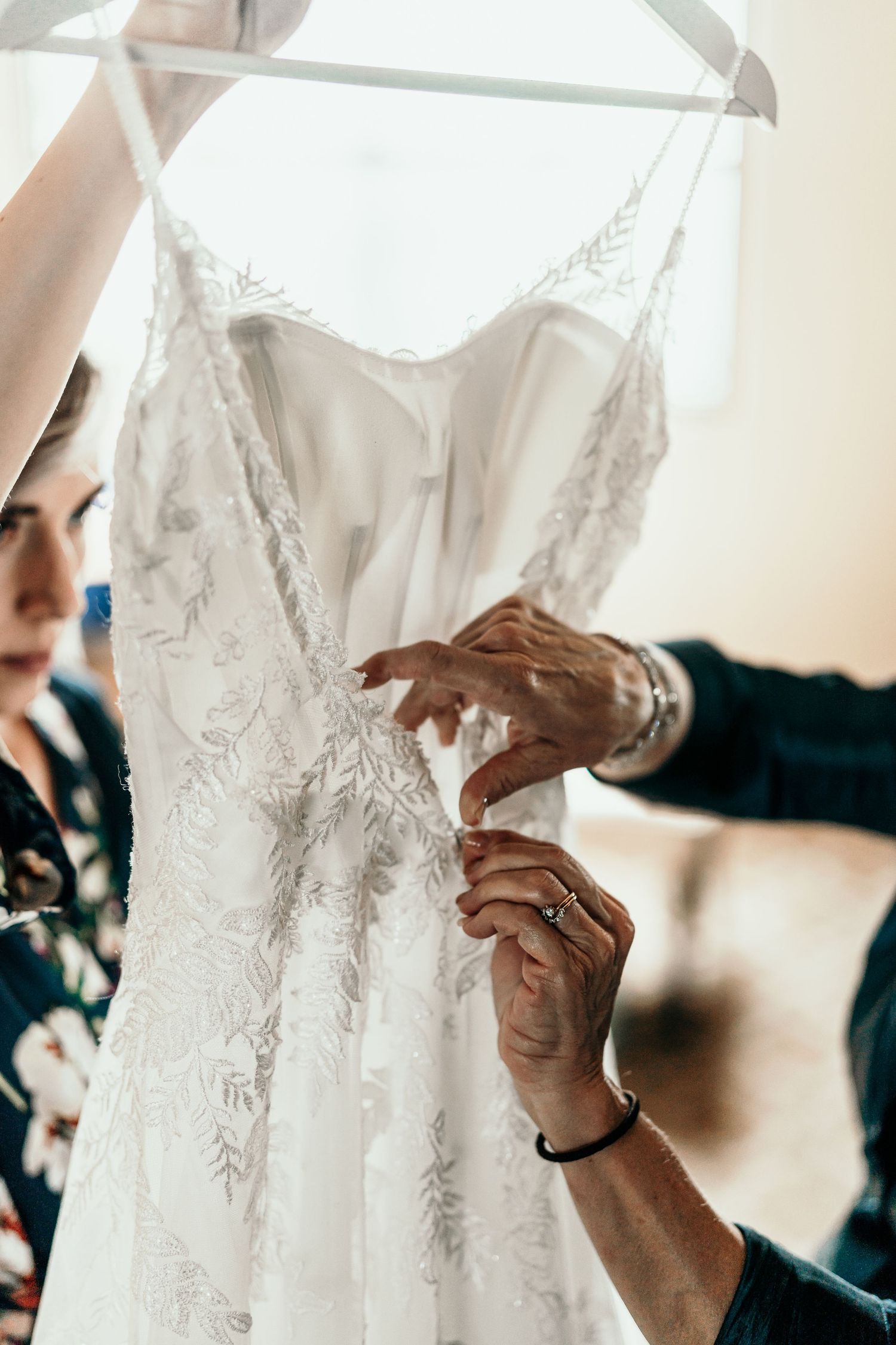 Close-up details of hands adjusting an intricate lace wedding dress.