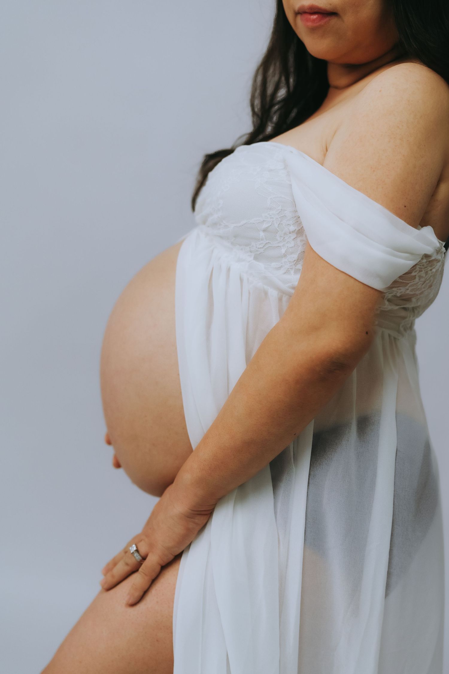 Progressive sideview photos of a pregnant belly in white maternity dress against neutral background.