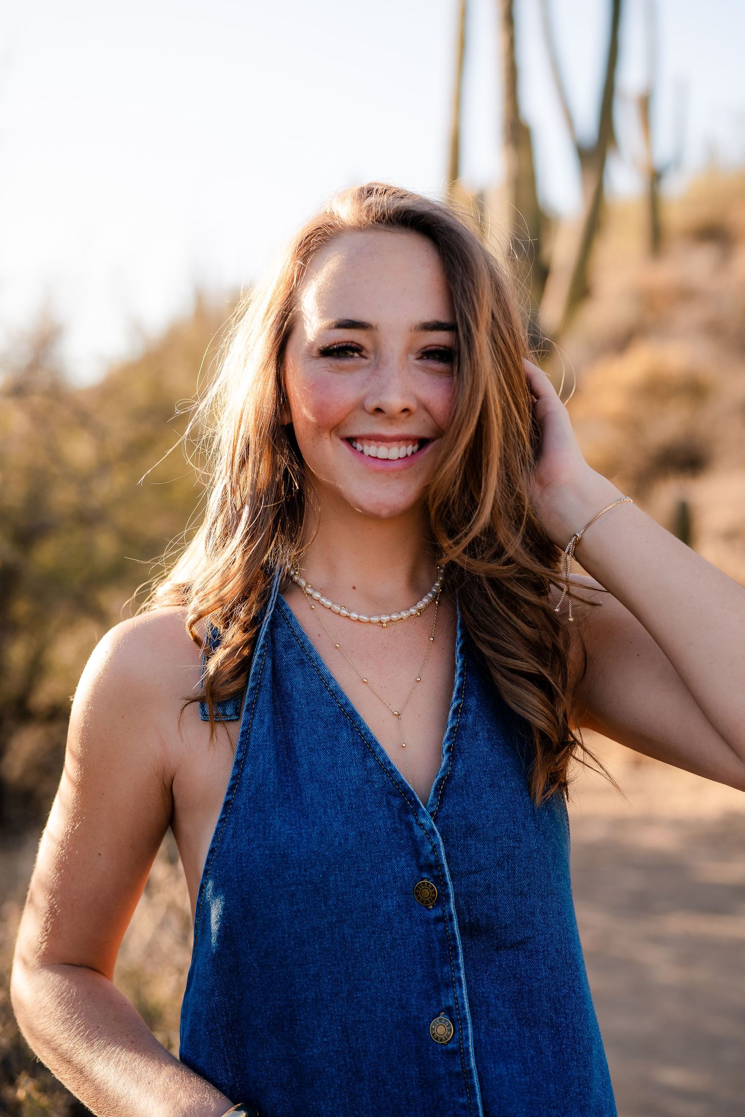 Portrait in desert setting showing person in denim top with natural lighting.