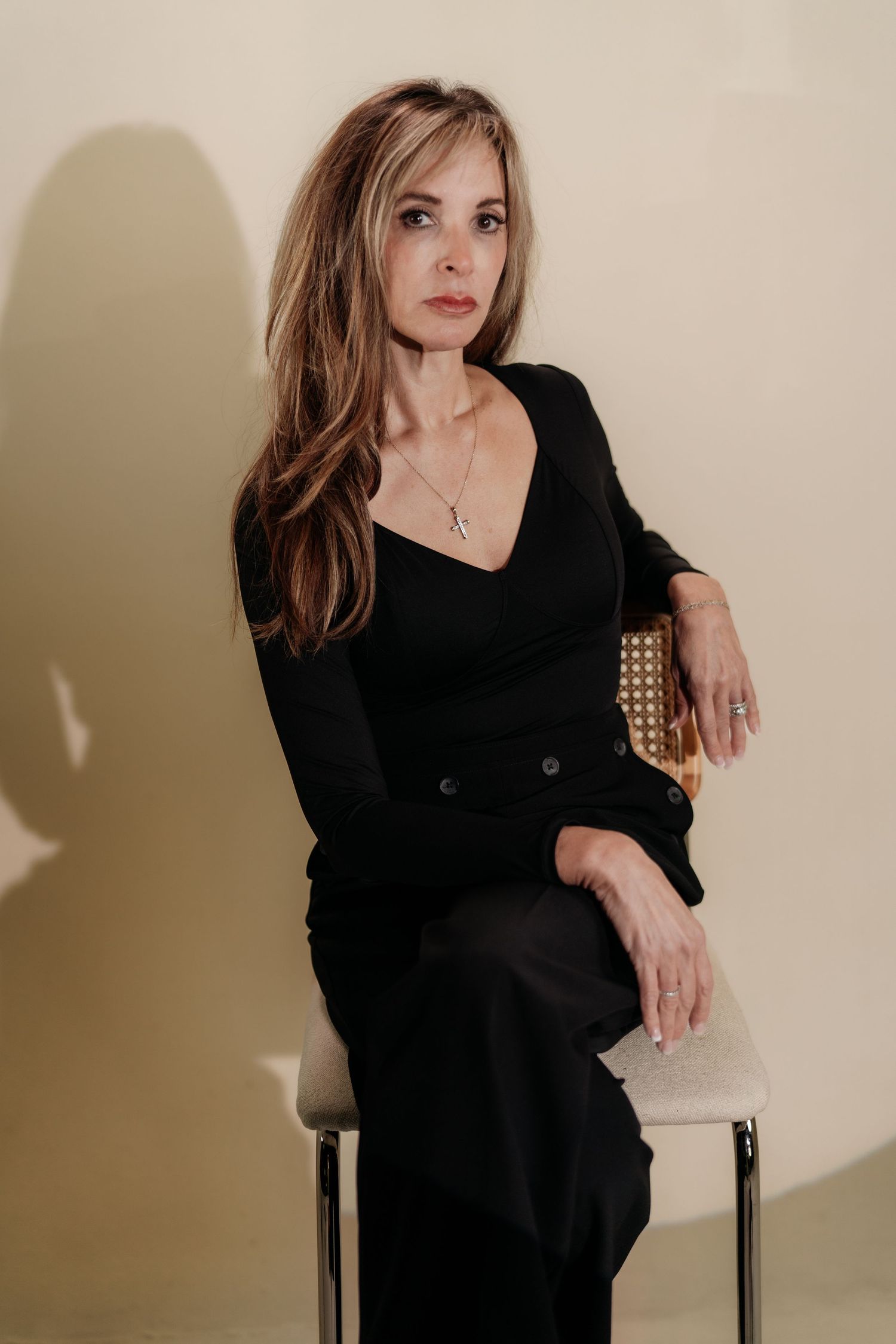 A woman in a black sweater poses against a beige wall in a series of artistic portrait shots.