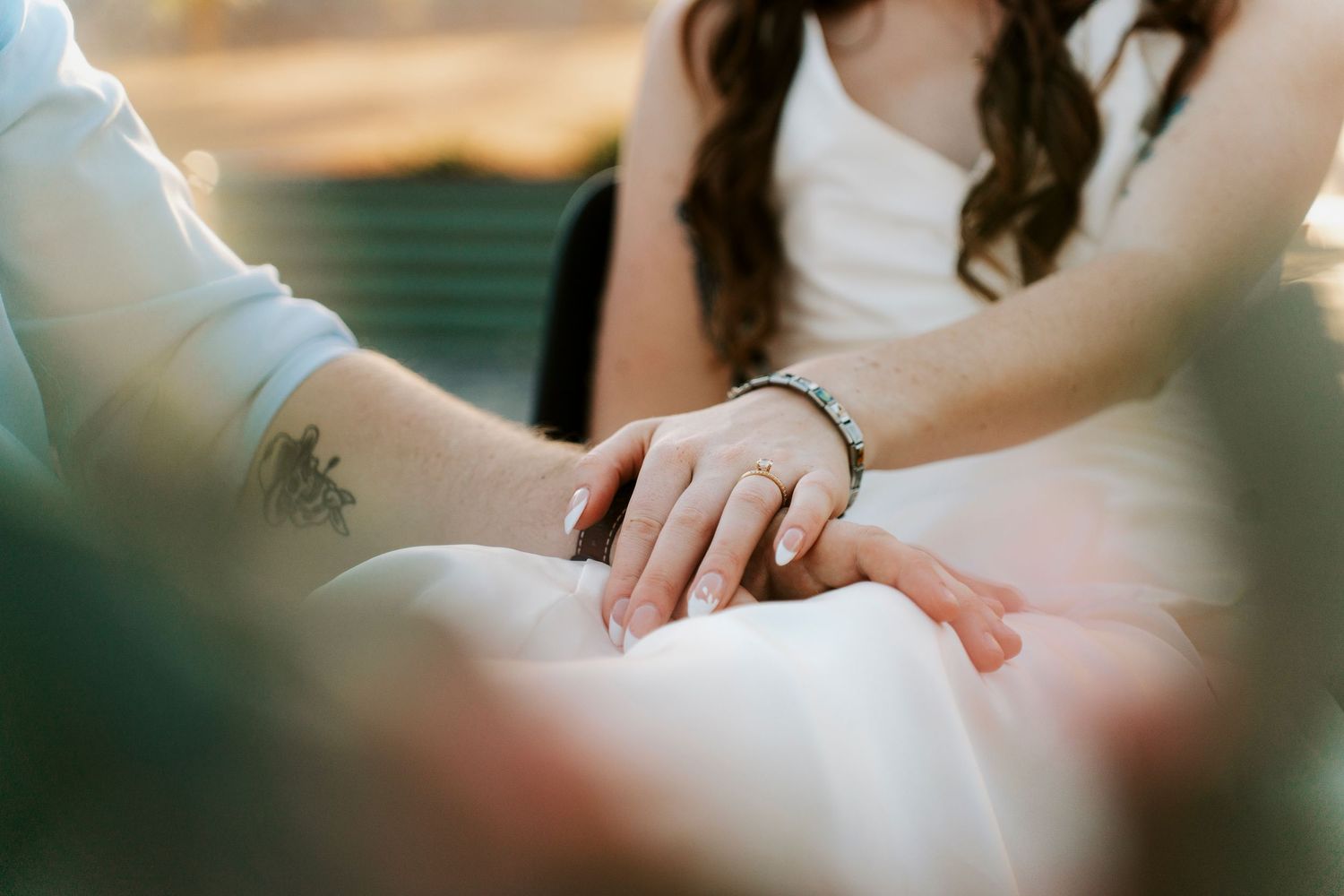 Close-up of hands with wedding rings resting on white fabric.