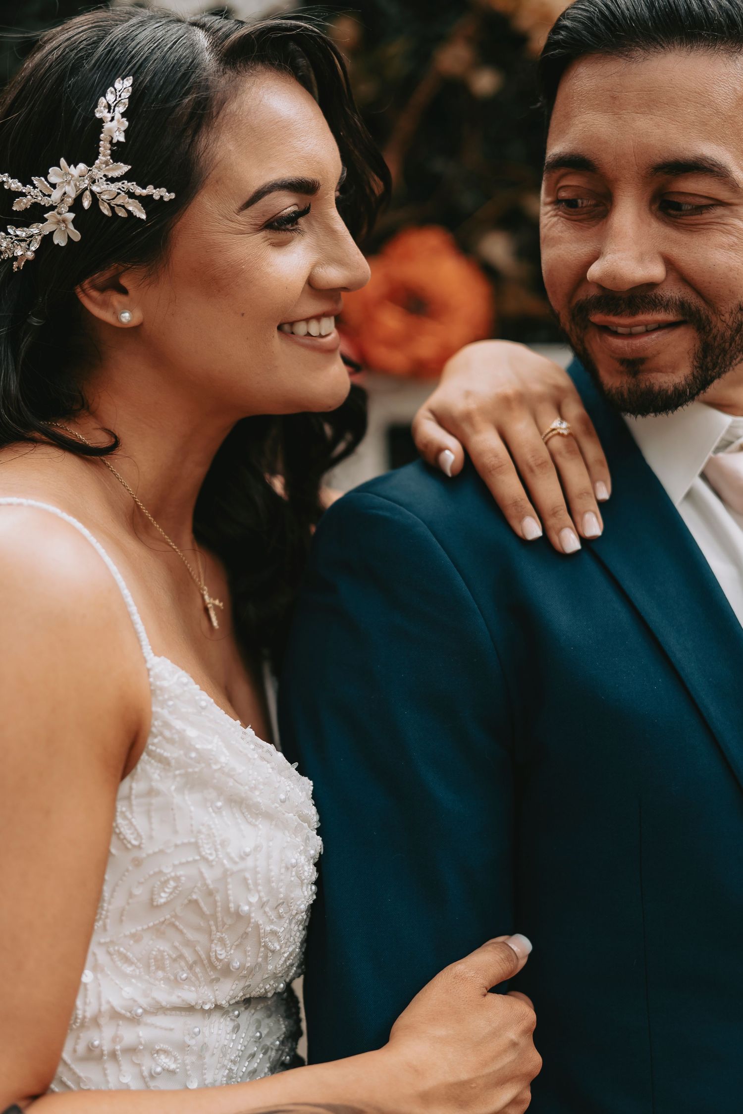 Wedding couple sharing an intimate moment wearing navy suit and white lace dress with crystal hairpiece.