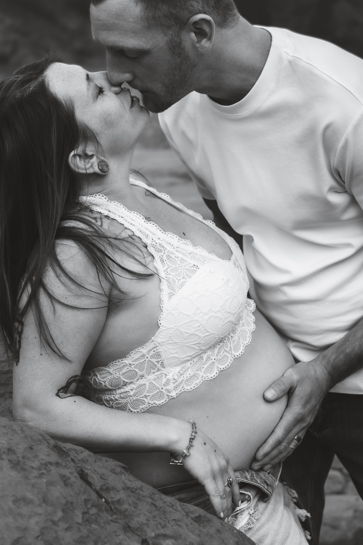 A romantic black and white photo of a couple embracing intimately, with the woman wearing a white lace top.