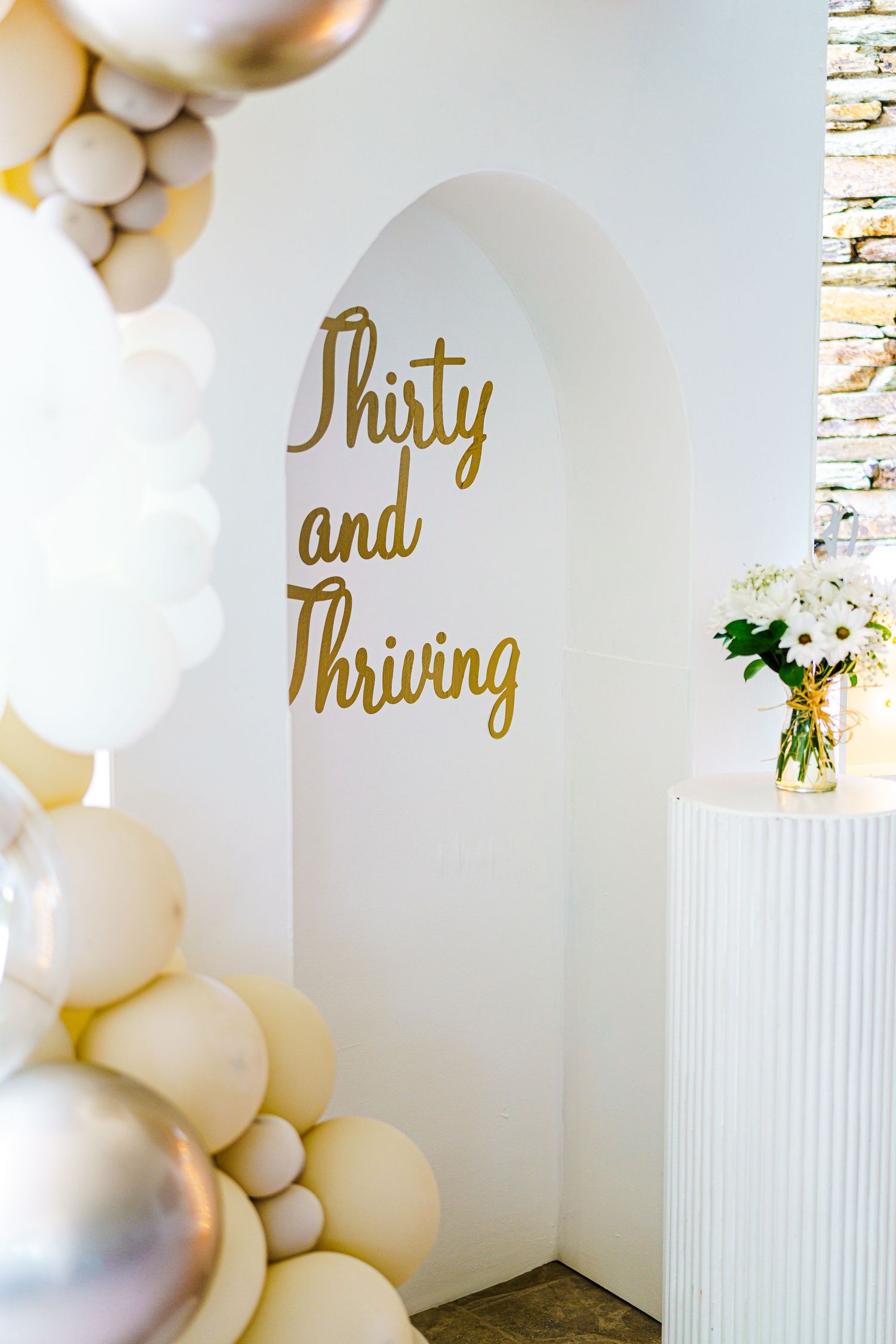 Gold 'Thirty and Thriving' text on white wall with elegant balloon arch decoration. Session in Phoenix Arizona