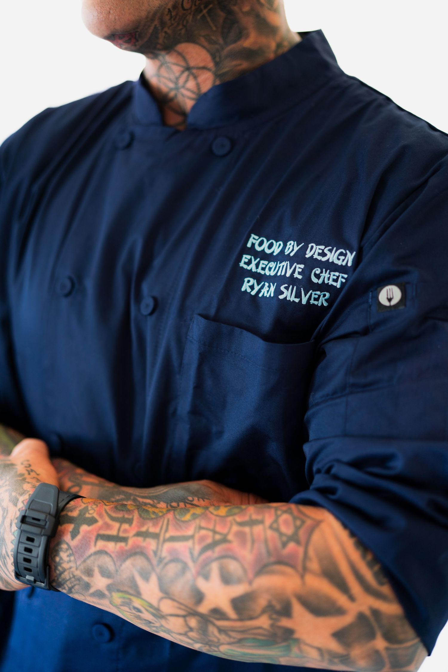 Chef coat with embroidered text and tattooed arms visible showing culinary professionalism. Session in Anthem Arizona