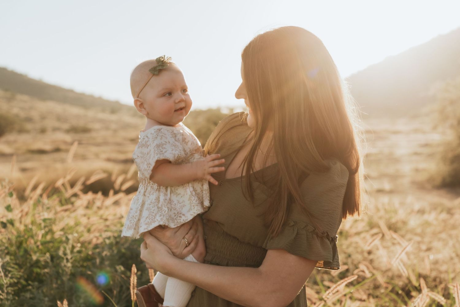 A family embraces during golden hour photography session in a desert landscape at sunset.