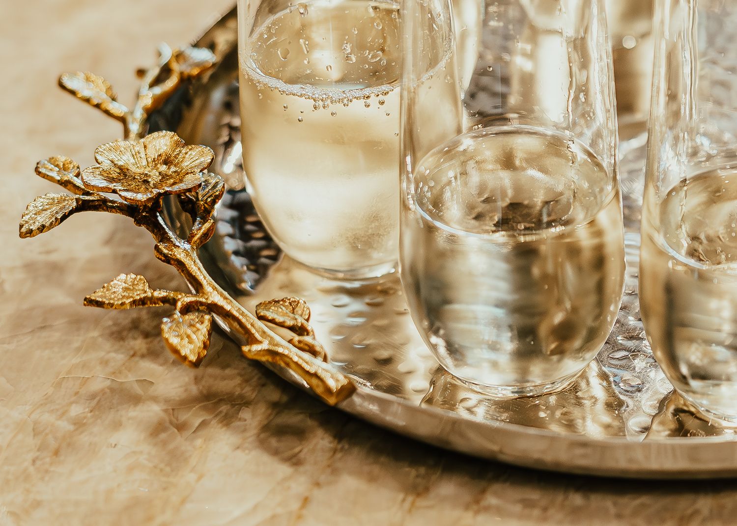 Elegant water glasses arranged on silver tray with decorative golden leaf accent. Session in Anthem Arizona