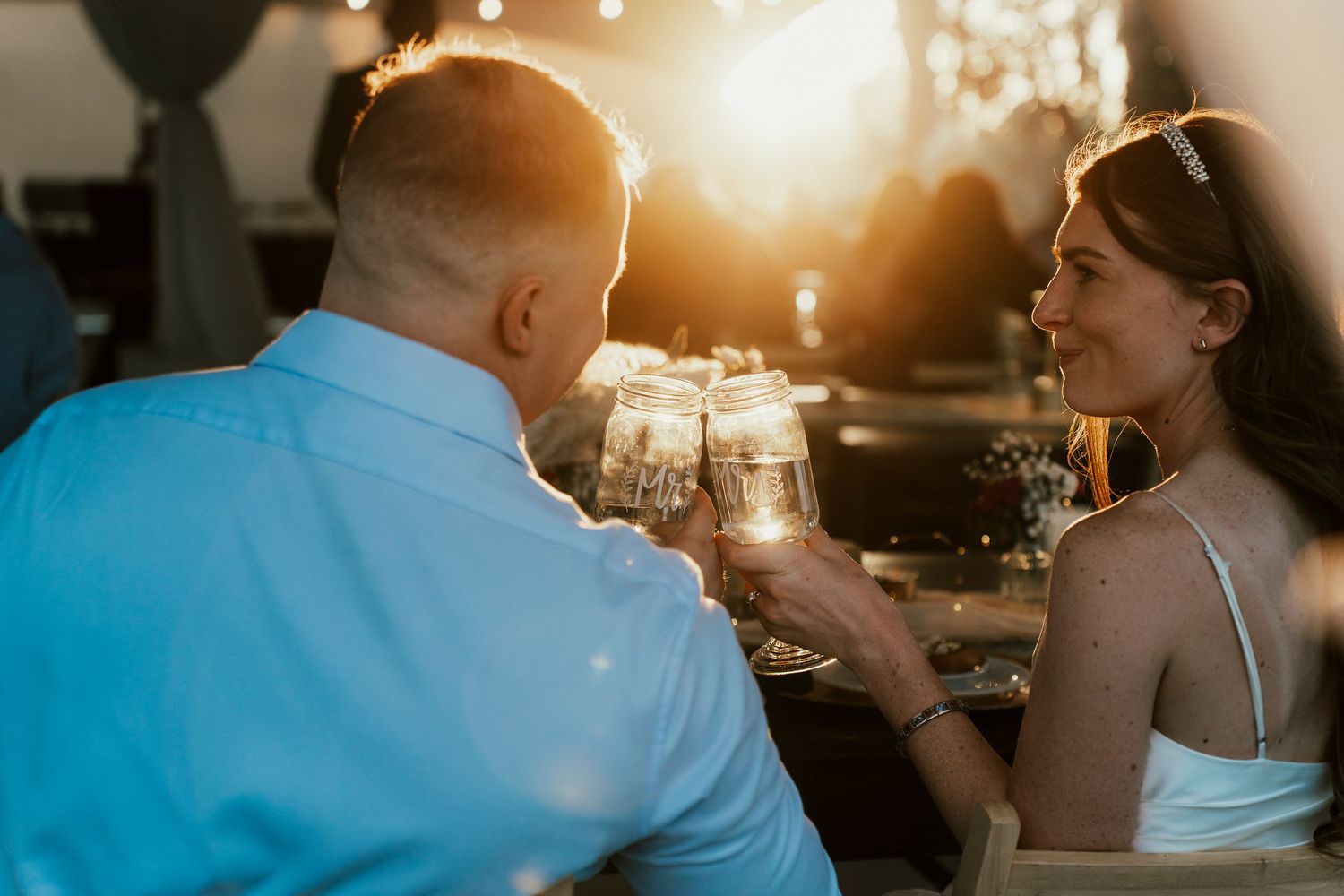 Two people share drinks at sunset with warm glowing lighting.