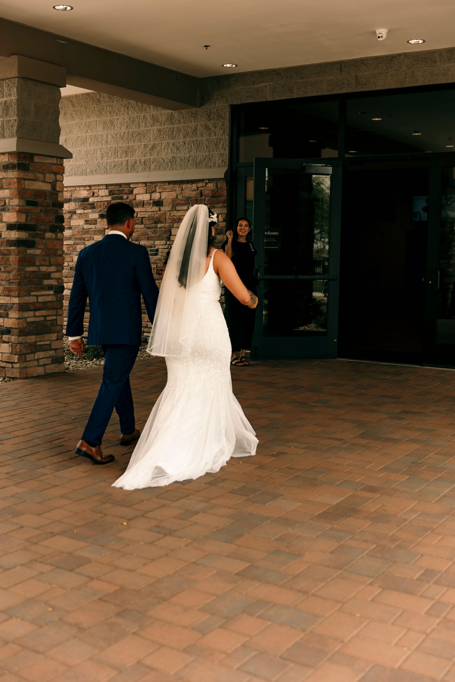 A couple walks away together on brick pavement after their wedding ceremony.