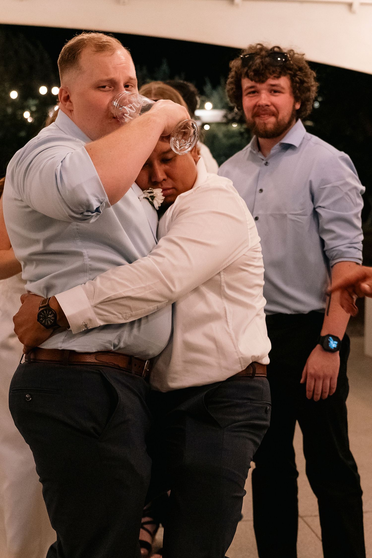 Wedding party members share embraces and celebrations during an indoor reception.