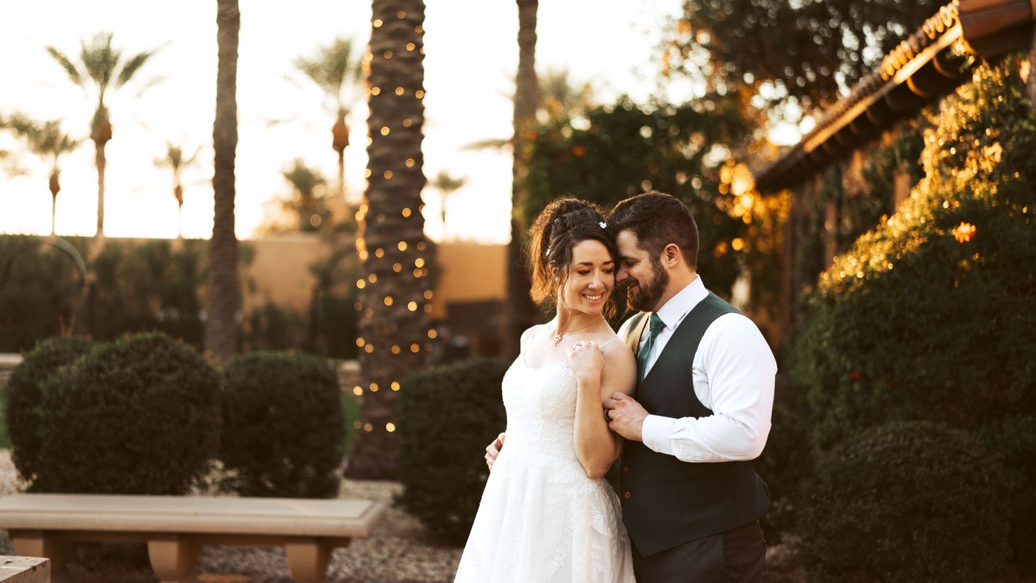 Romantic sunset moment between wedding couple with palm trees in background.