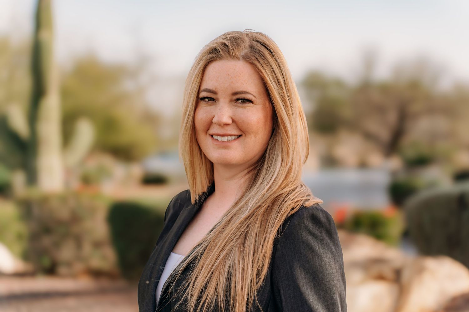 Professional headshot of businesswoman in dark blazer against desert landscape. Session in Anthem Arizona
