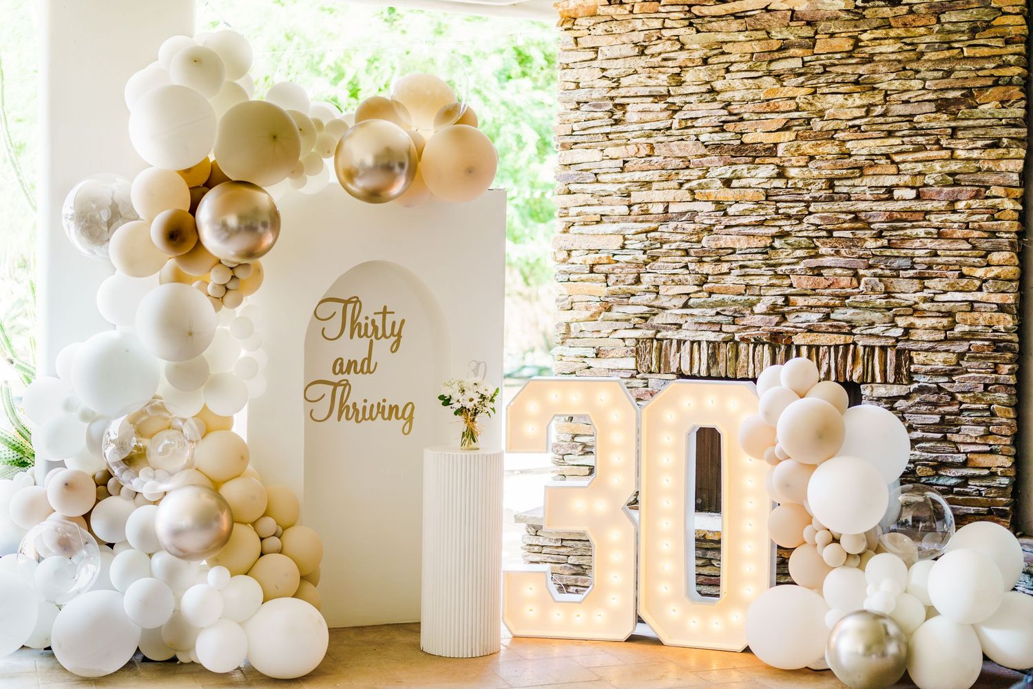 Luxury event space decorated with white and gold balloon installations against stone wall. Session in Phoenix Arizona