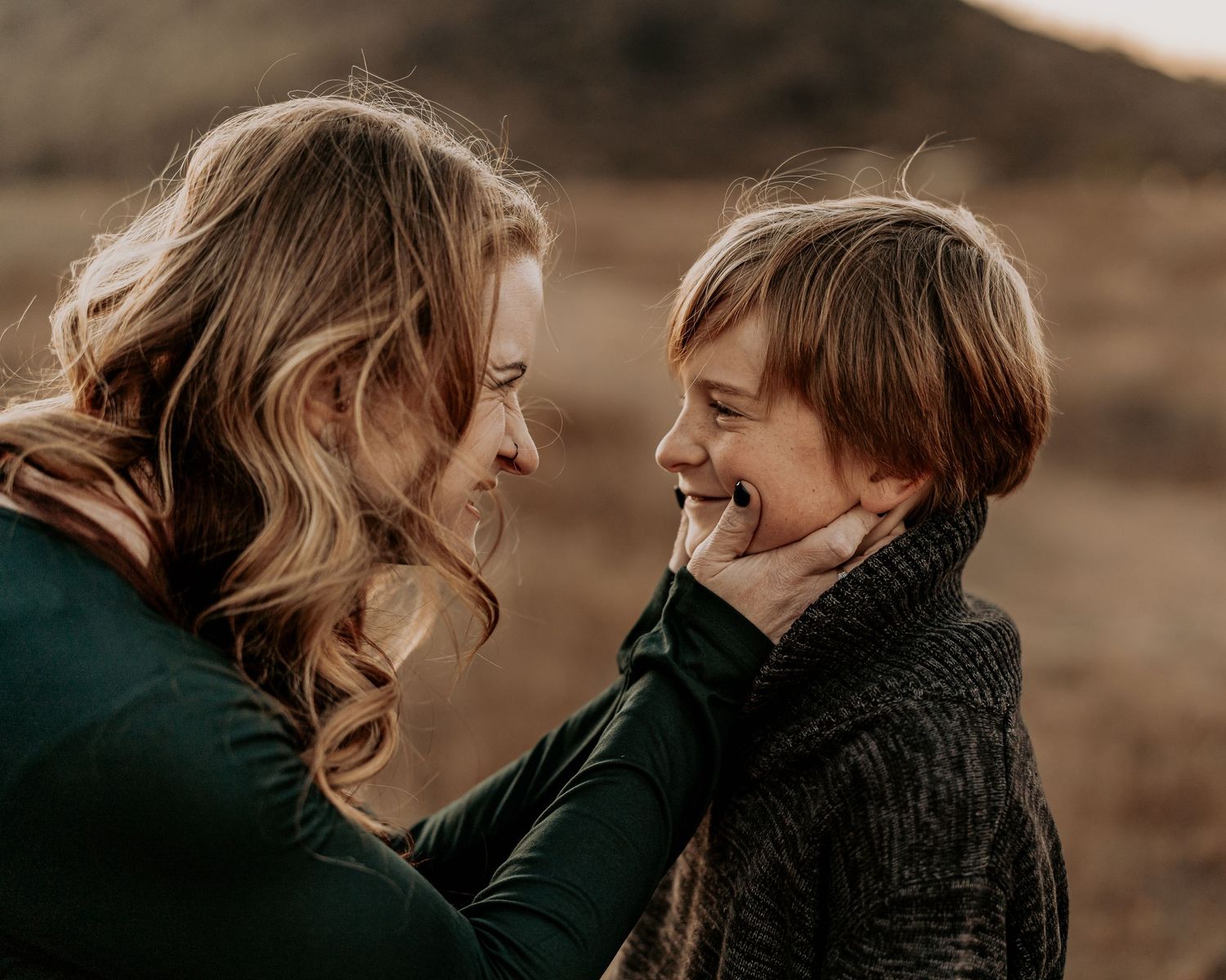 Intimate moment of shared joy between parent and child against mountain backdrop.