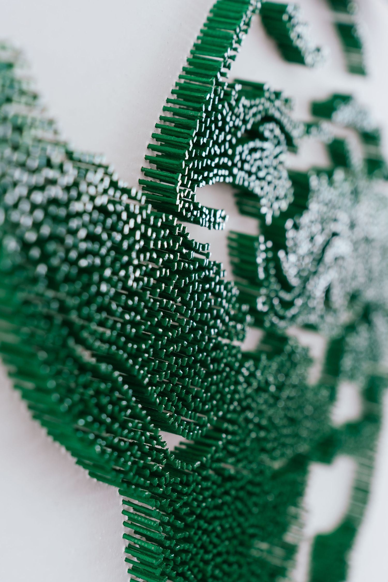 Close-up view of green geometric abstract pattern with textured surfaces creating a dynamic ripple effect.