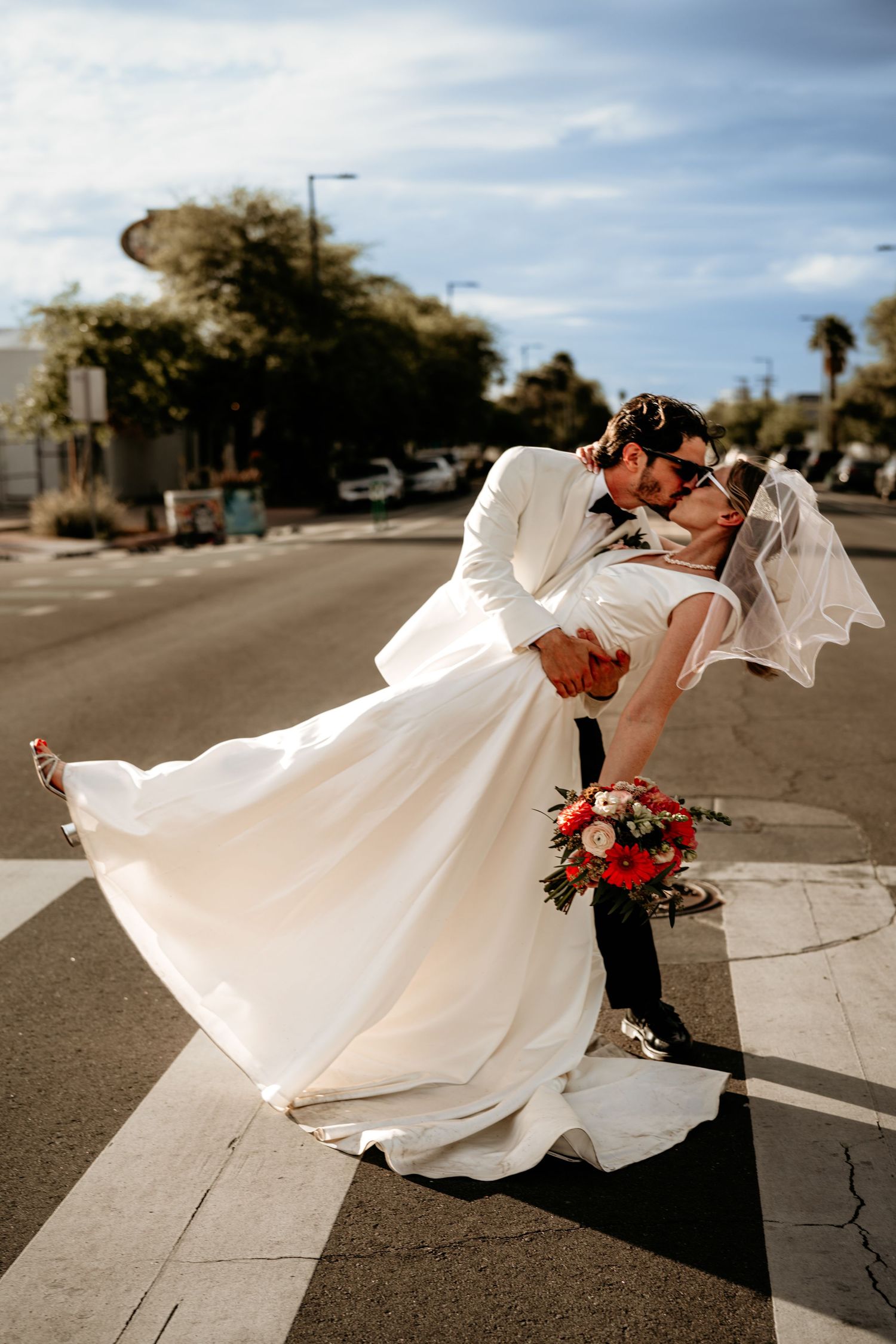 A dramatic dip pose on a city street with the bride's dress flowing in elegant white.