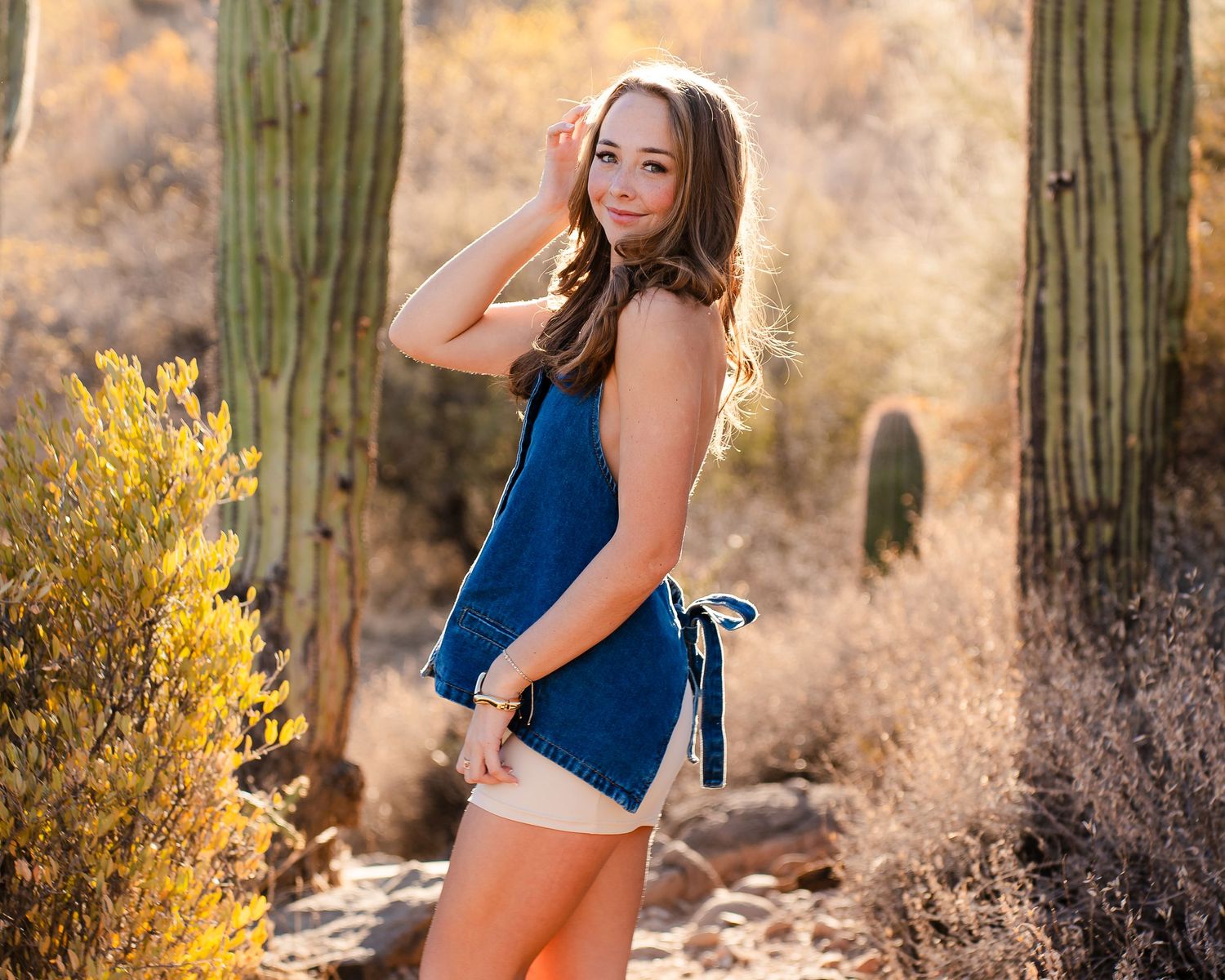 Desert photography session featuring casual denim outfit among saguaro cacti.