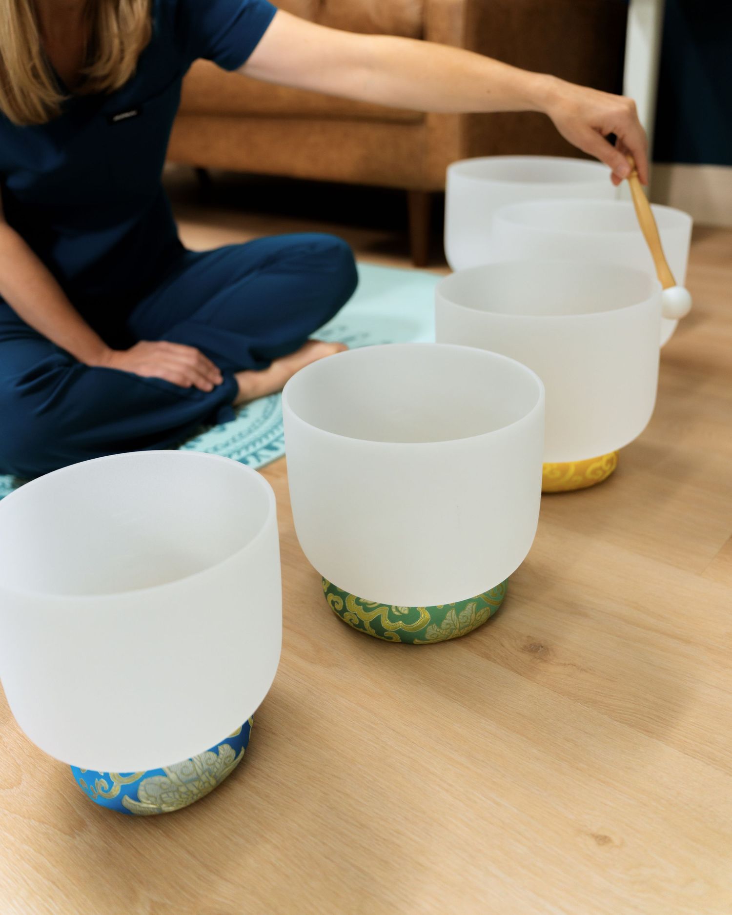 Several white crystal singing bowls arranged on a wooden table for sound healing or meditation practice.