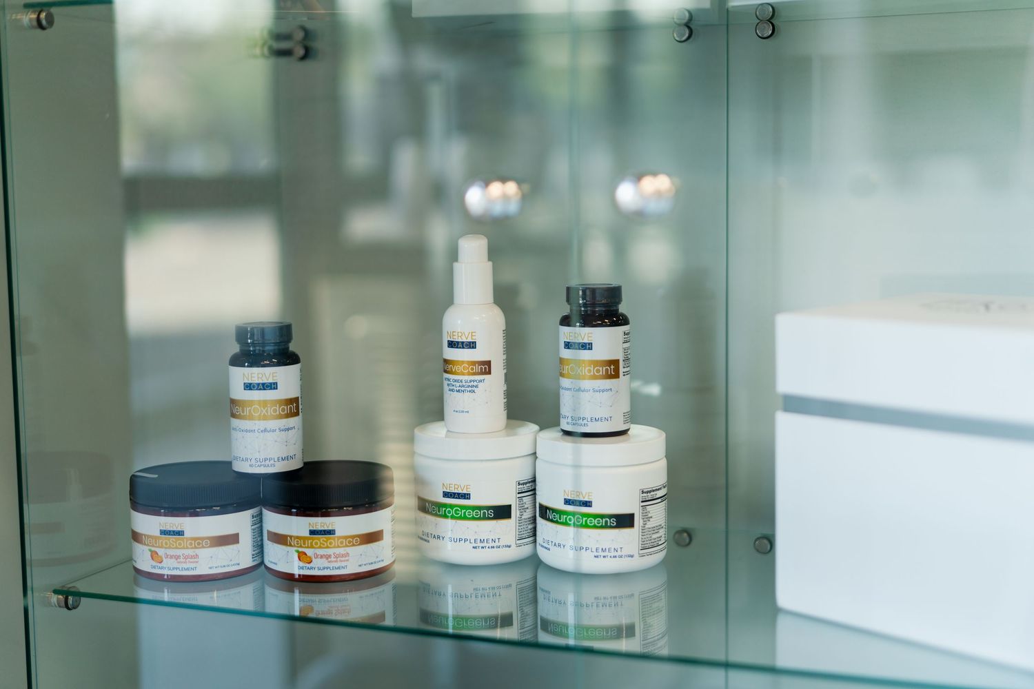 Various skincare and cosmetic products arranged on a glass shelf in a medical or spa setting.