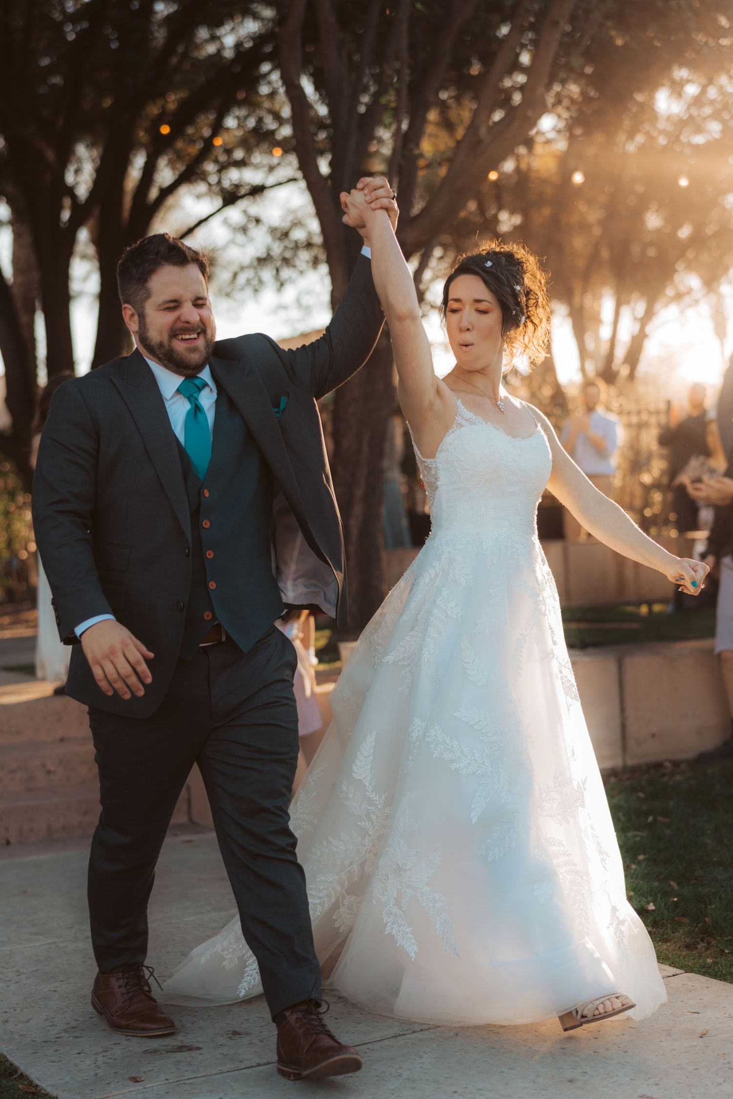 Joyful couple dancing together outdoors during sunset celebration.