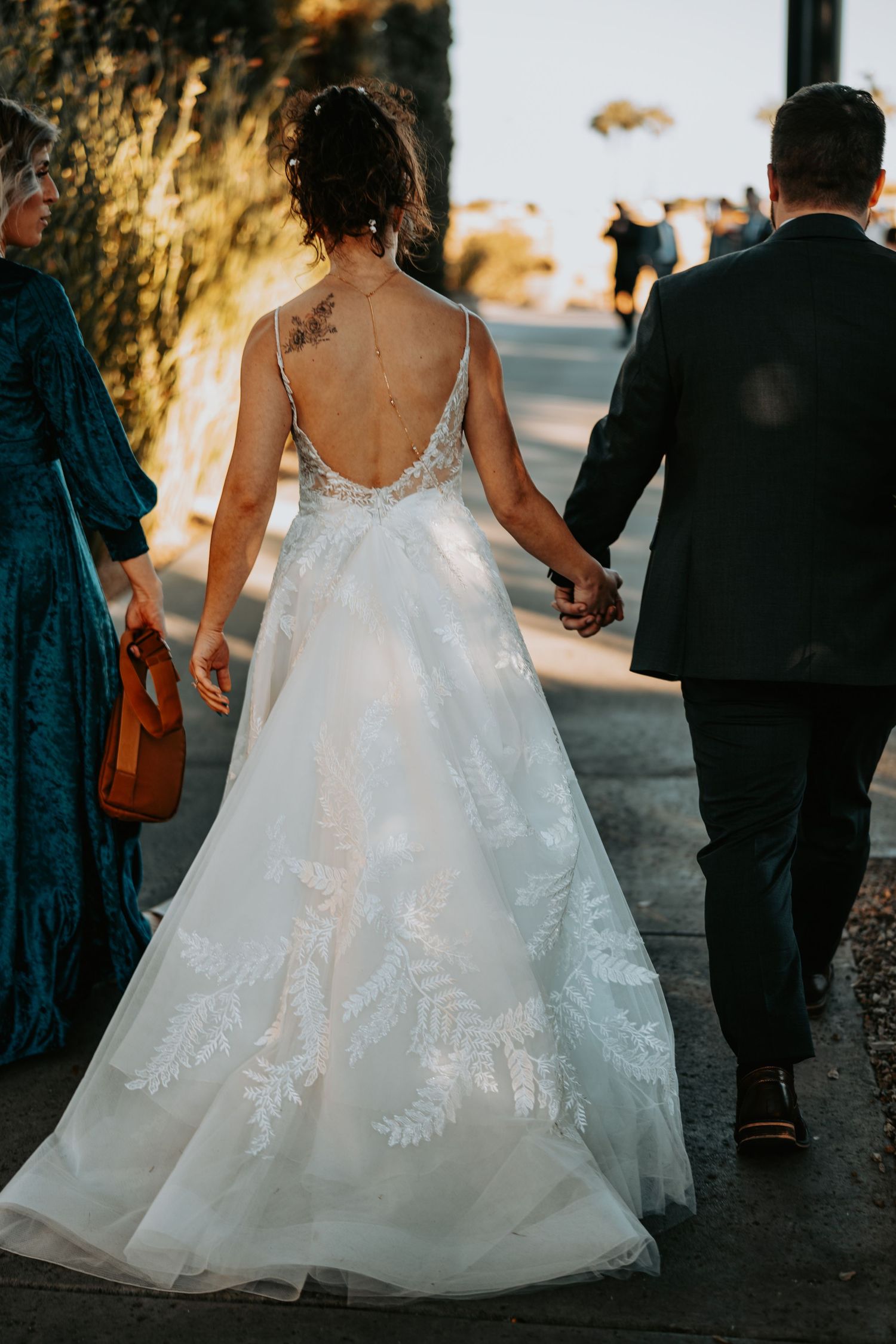 Close-up of intricate lace details on flowing white wedding dress from behind.