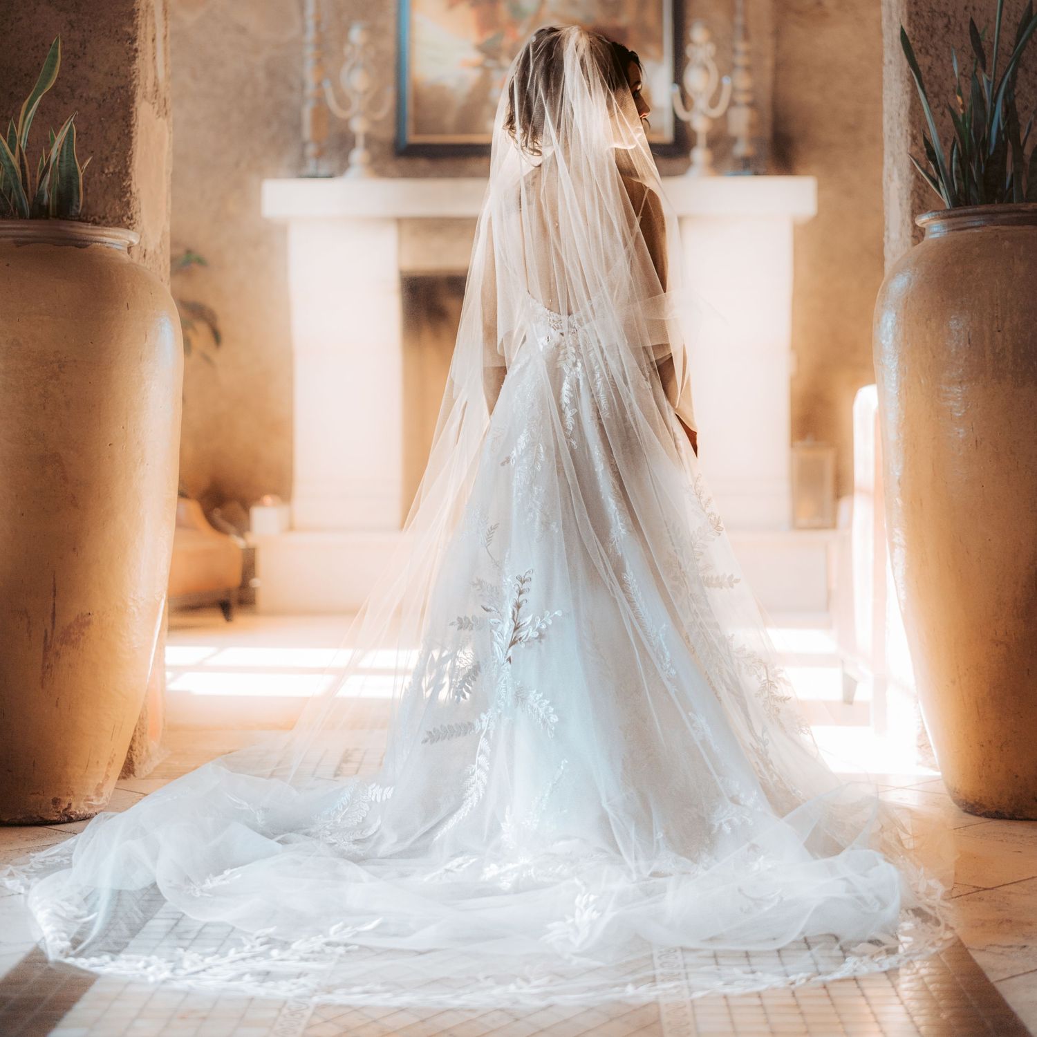 Elegant white wedding dress with long train photographed in natural window light.
