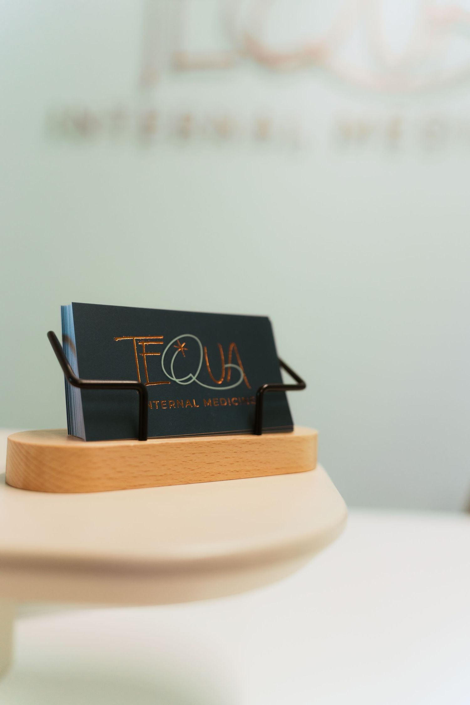 Close-up view of black business cards on a curved wooden surface showing minimal branding design details.