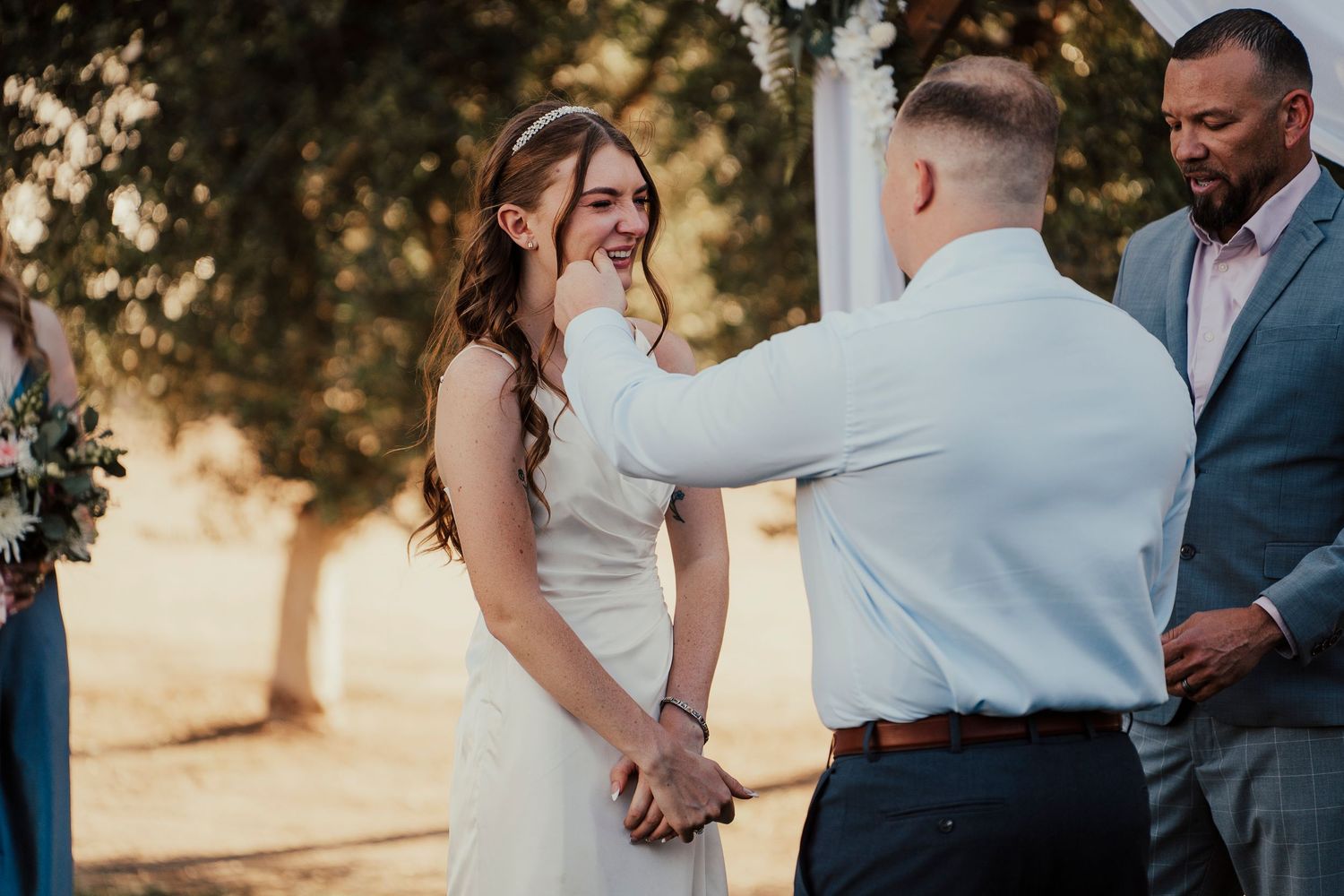 Wedding party members share casual moments during an outdoor ceremony.