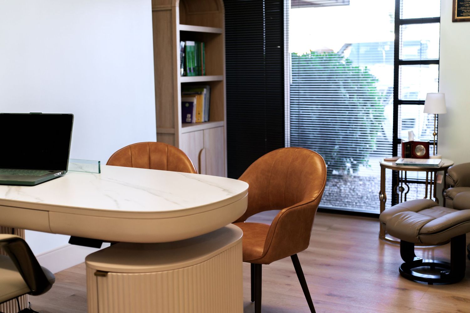 A modern minimalist living space with curved white walls and brown leather chairs in an open-plan layout.
