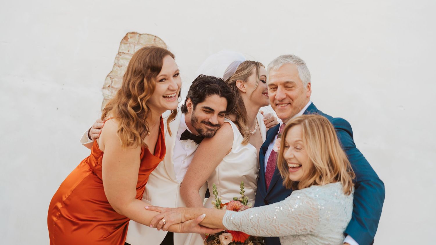 Wedding guests share joyful embraces and laughter during celebration.
