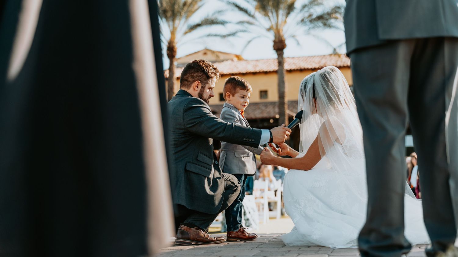 Intimate wedding ceremony moment under palm trees during golden hour.