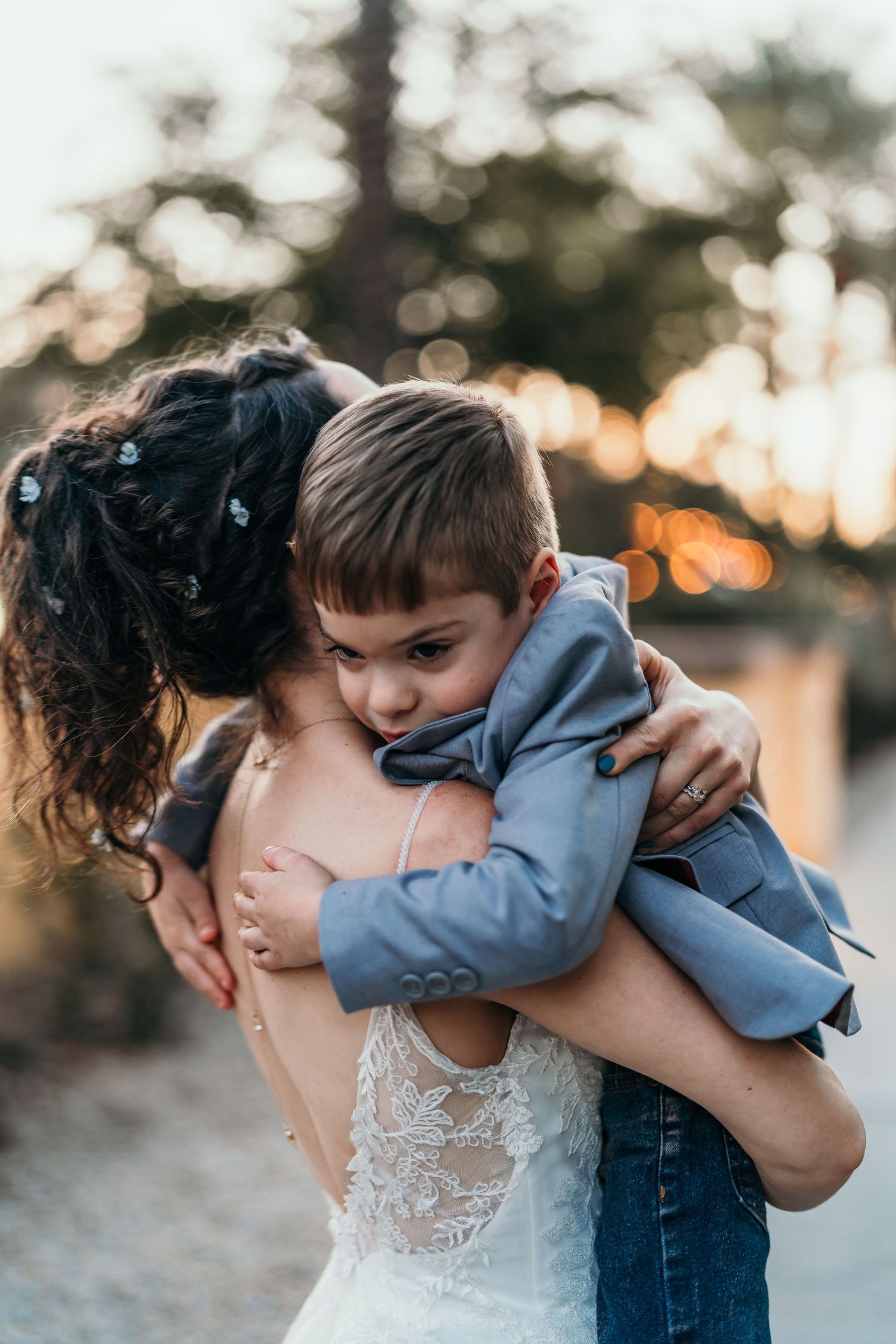 Tender moment captured during outdoor wedding ceremony in warm sunset lighting.