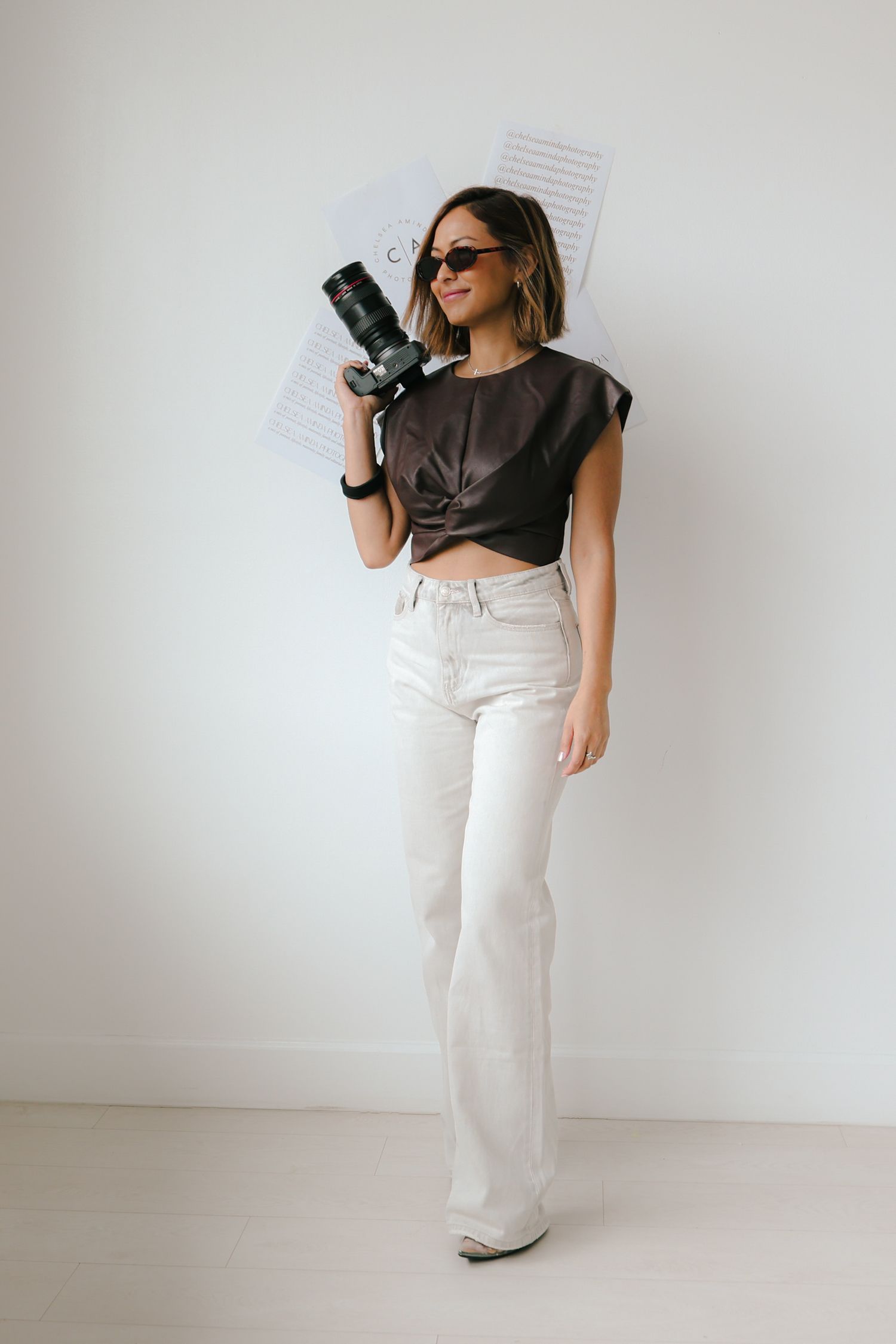 A fashion model wearing a brown t-shirt and white high-waisted pants poses in different angles against a white background.