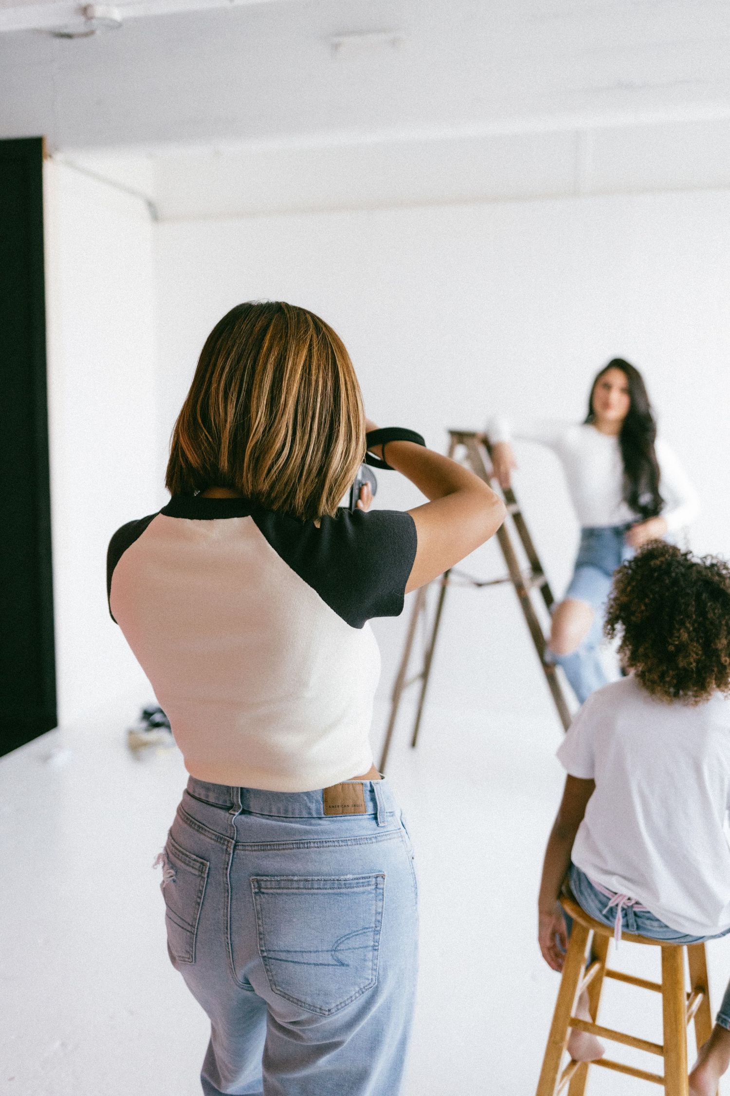 Artists working at white easels in a bright studio space wearing casual white tops and jeans.
